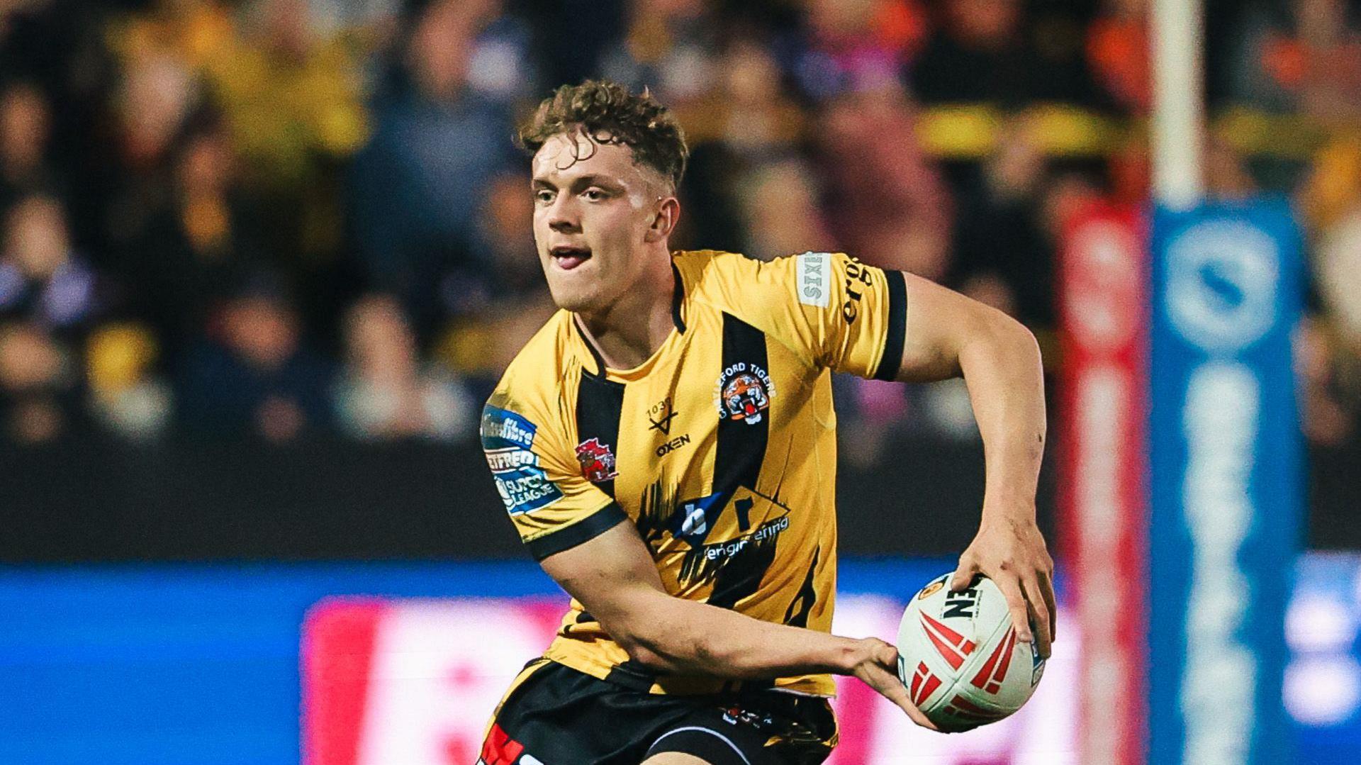 Fletcher Rooney running with the ball in a Castleford Tigers yellow and black kit