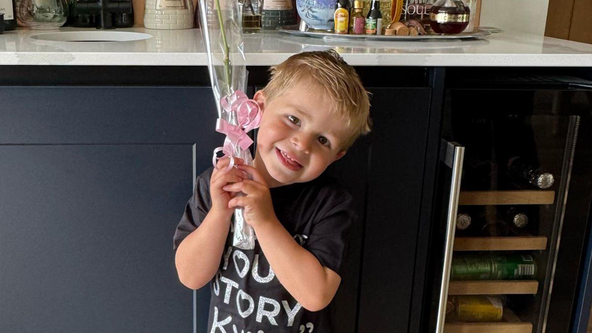 Three-year-old Reuben posing with a pink rose