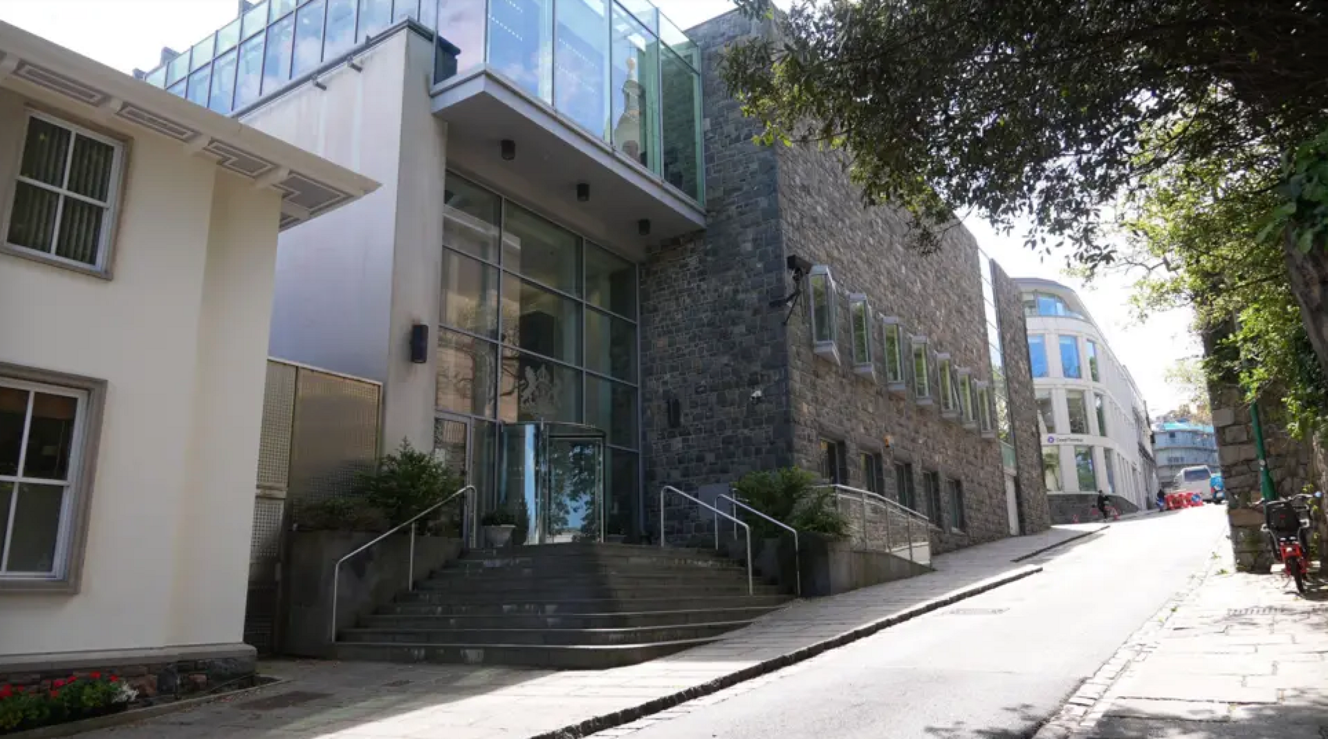 The exterior of Guernsey Magistrates Court. There is a road outside it and two buildings either side of it. 