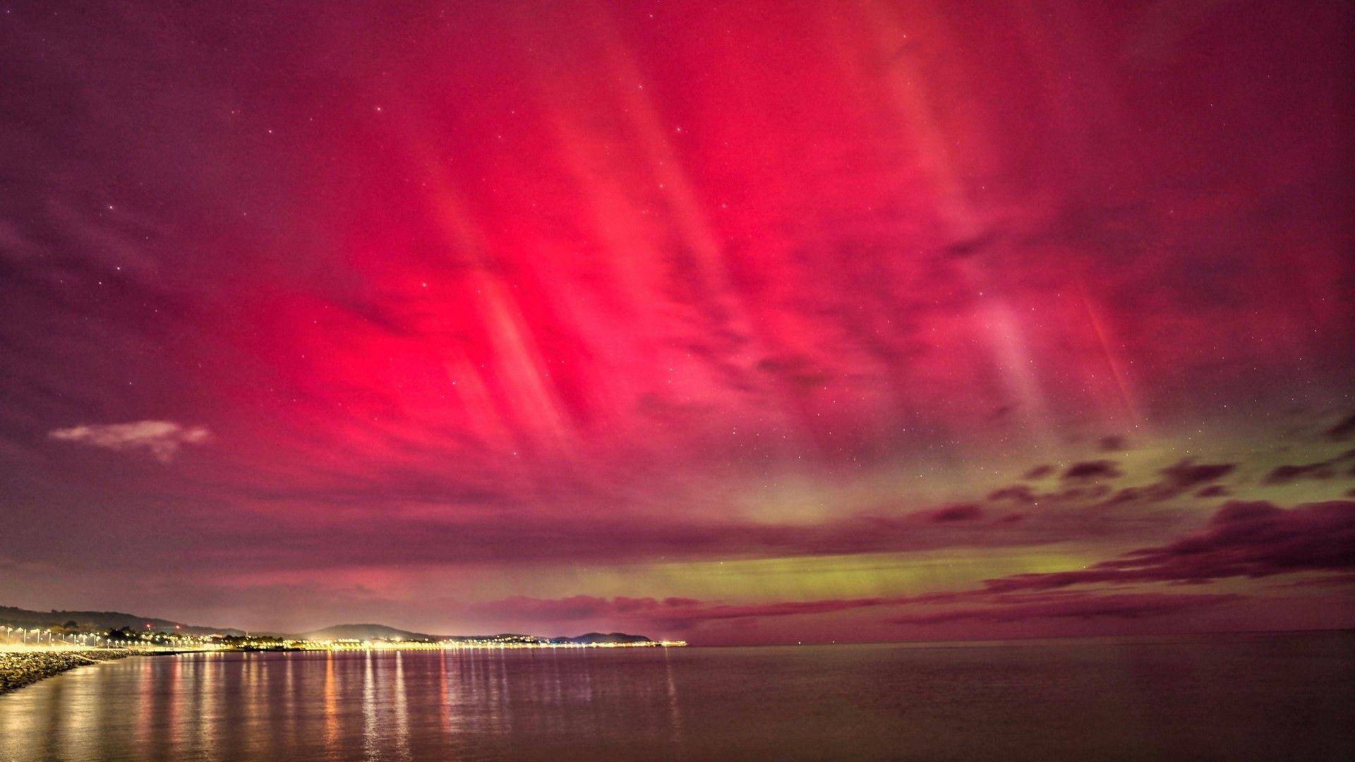 Red, pink and green colour the night sky on the North Wales coast