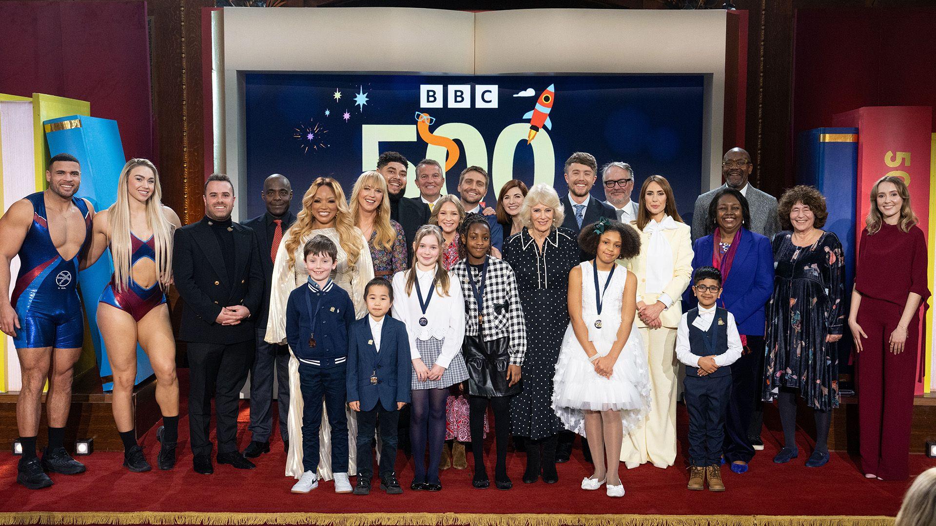 Picture shows: Back: Gladiators Steel and Diamond, Rob Eckland, Paterson Joseph, Marisha Wallace, Sara Cox, Big Zuu, Bradley Walsh, Joanna Page, Barney Walsh, Jodie Whittaker, Her Majesty The Queen, Roman Kemp, Charlie Higson, Alex Jones, Malorie Blackman, Lenny Henry, Francesca Simon, Rose Ayling-Ellis. Front: BBC 500 Words 2026 winners Harry Hart, Zuren Zhang, Ariadne Elena Livas, Annalise Ikeasomba, Maya Ukwubiwe, Muhammed-Da’oud Khan. 