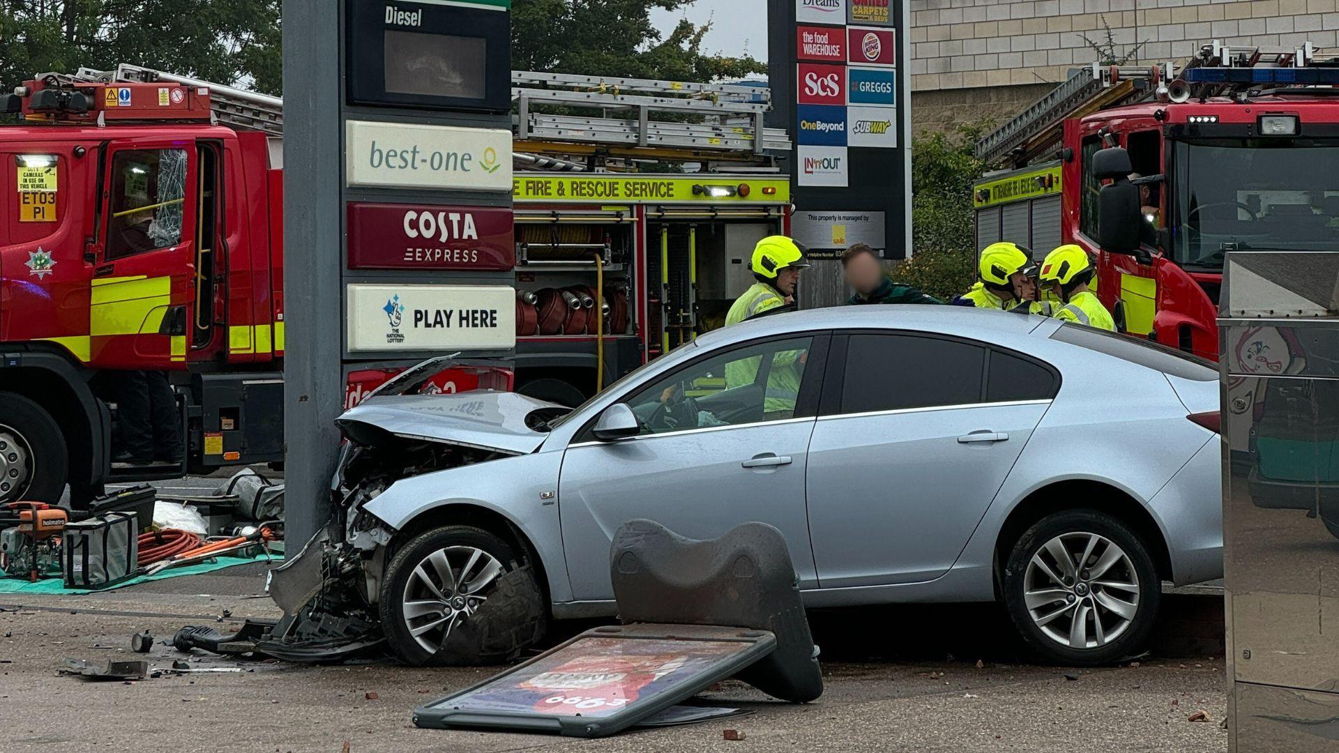 A crumpled car crashed into a petrol station sign