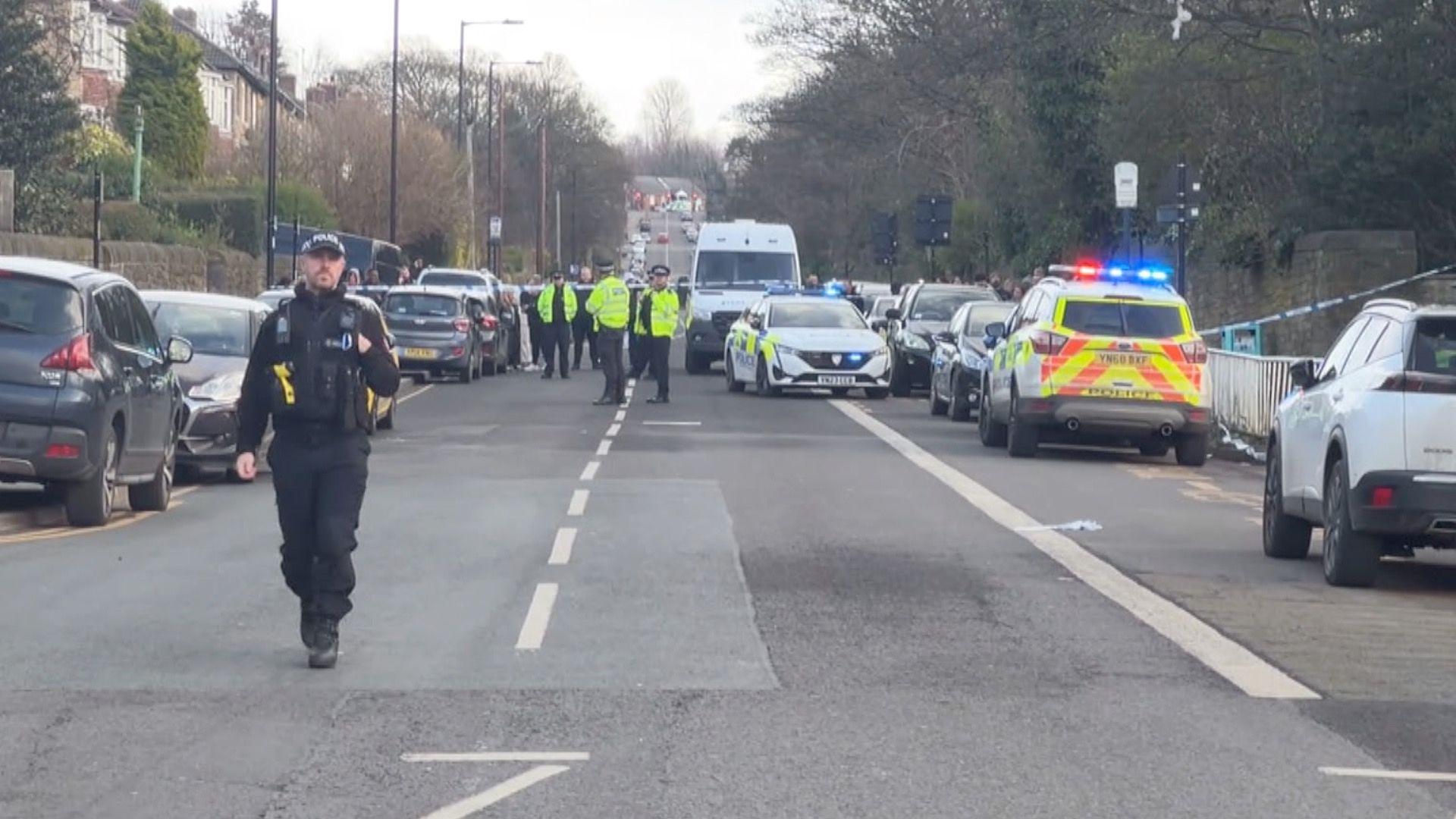 A street full with police vehicles and a police officer in uniform walking down the road