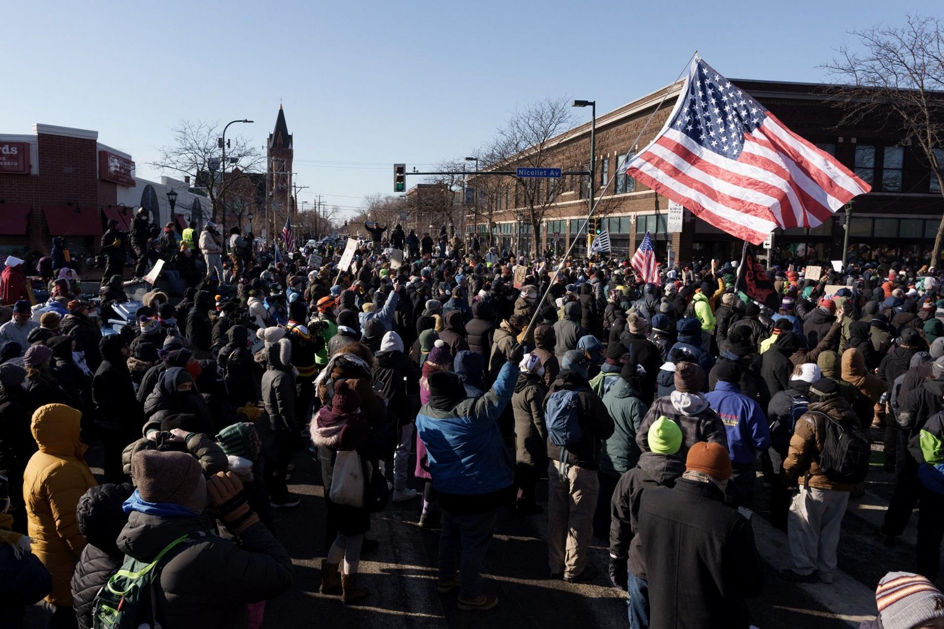 Protestors marching on Nicollet Avenue in Minneapolis, including one carrying a large US flag