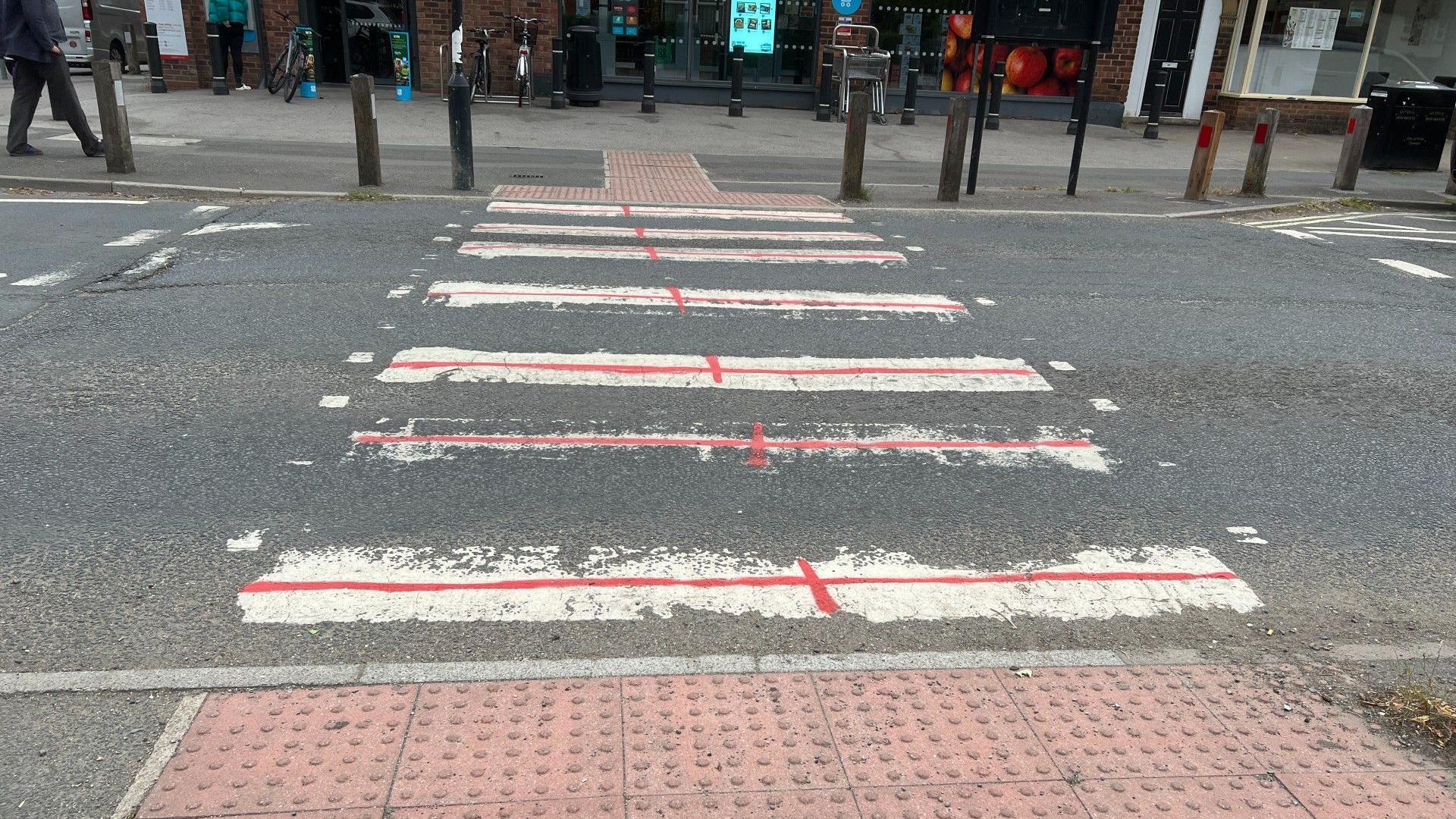 Red paint in the shape of England flags on a zebra crossing.
