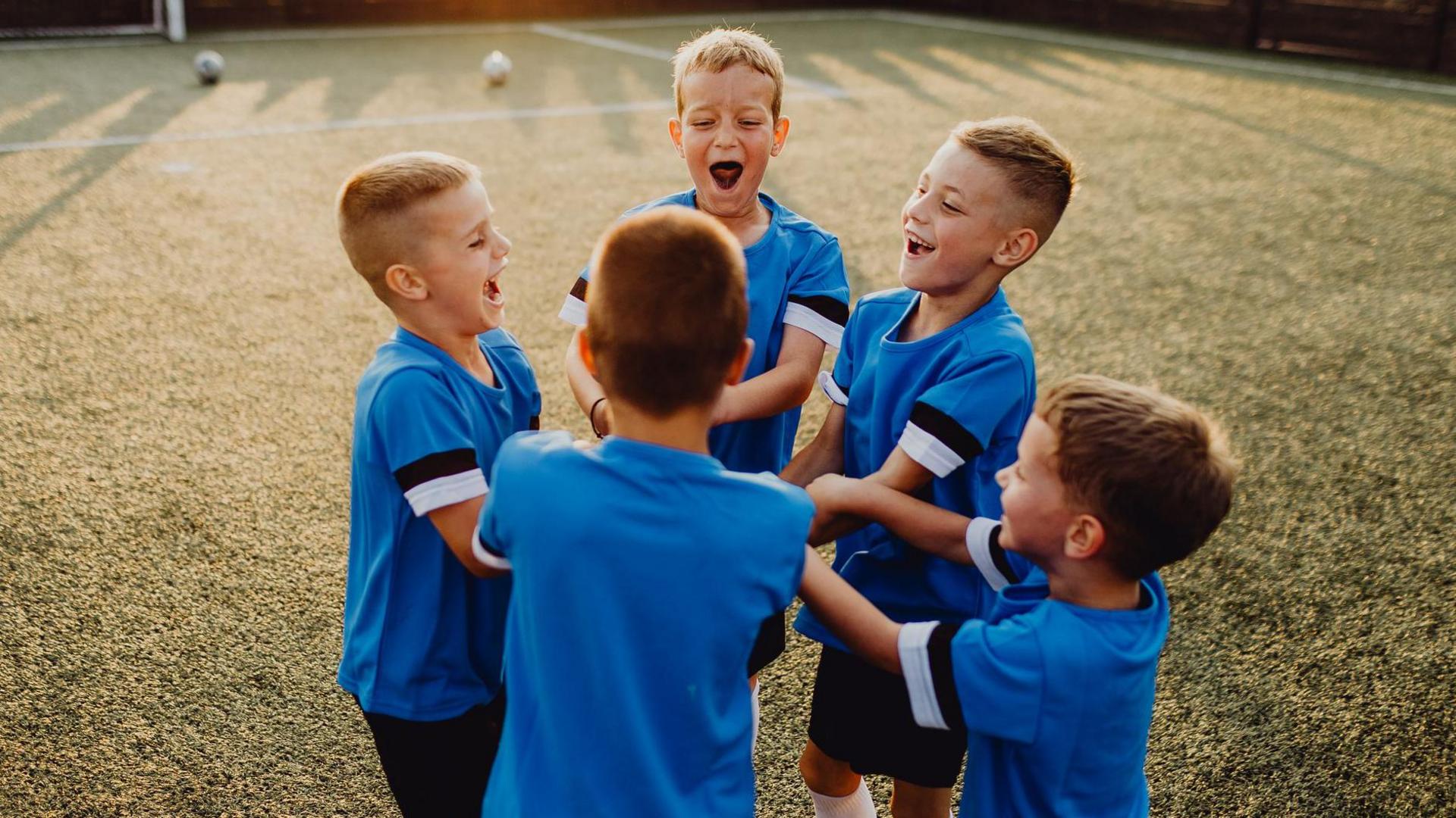 Group of junior soccer team players huddling on sports field - stock photo
