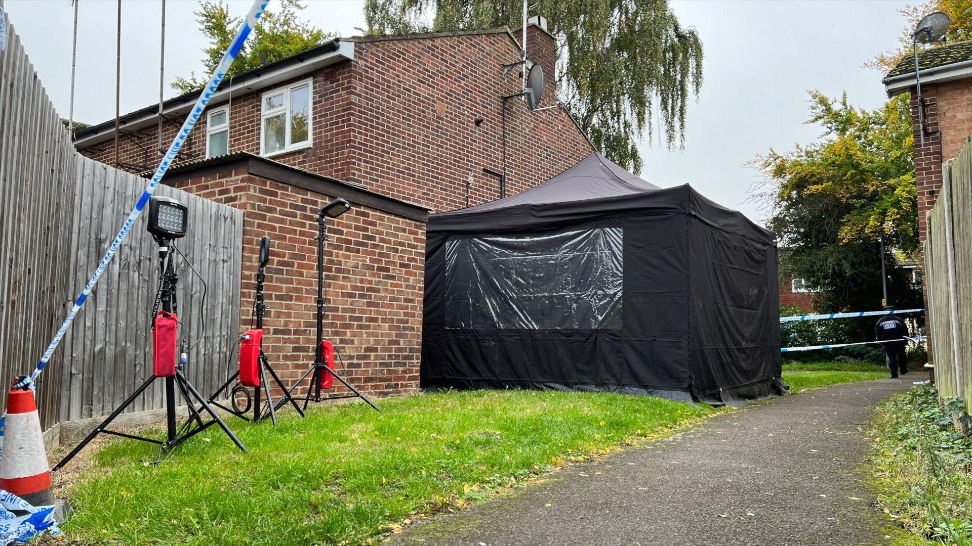 A black police tent and police cordon on Meadgate Avenue.