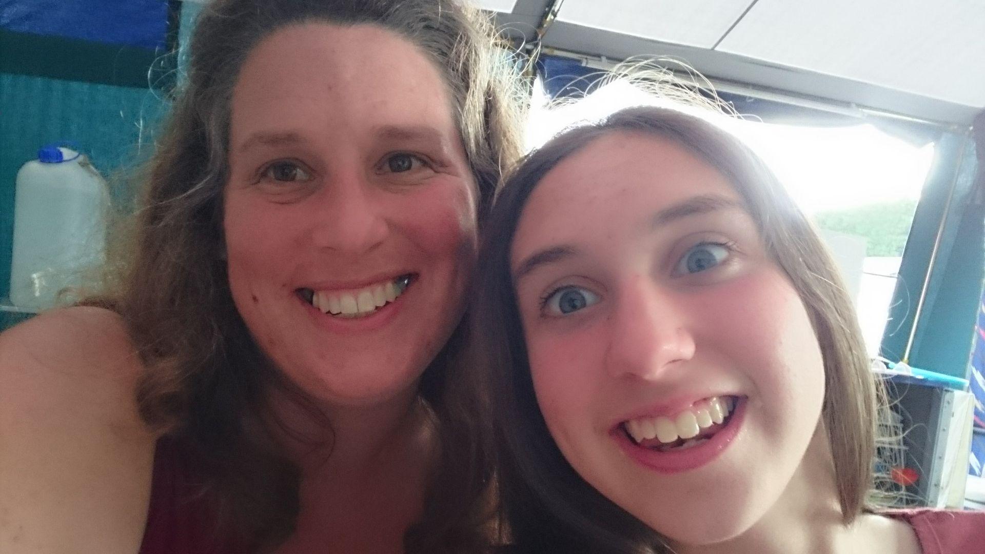 A mother and daughter smile widely in a selfie. 