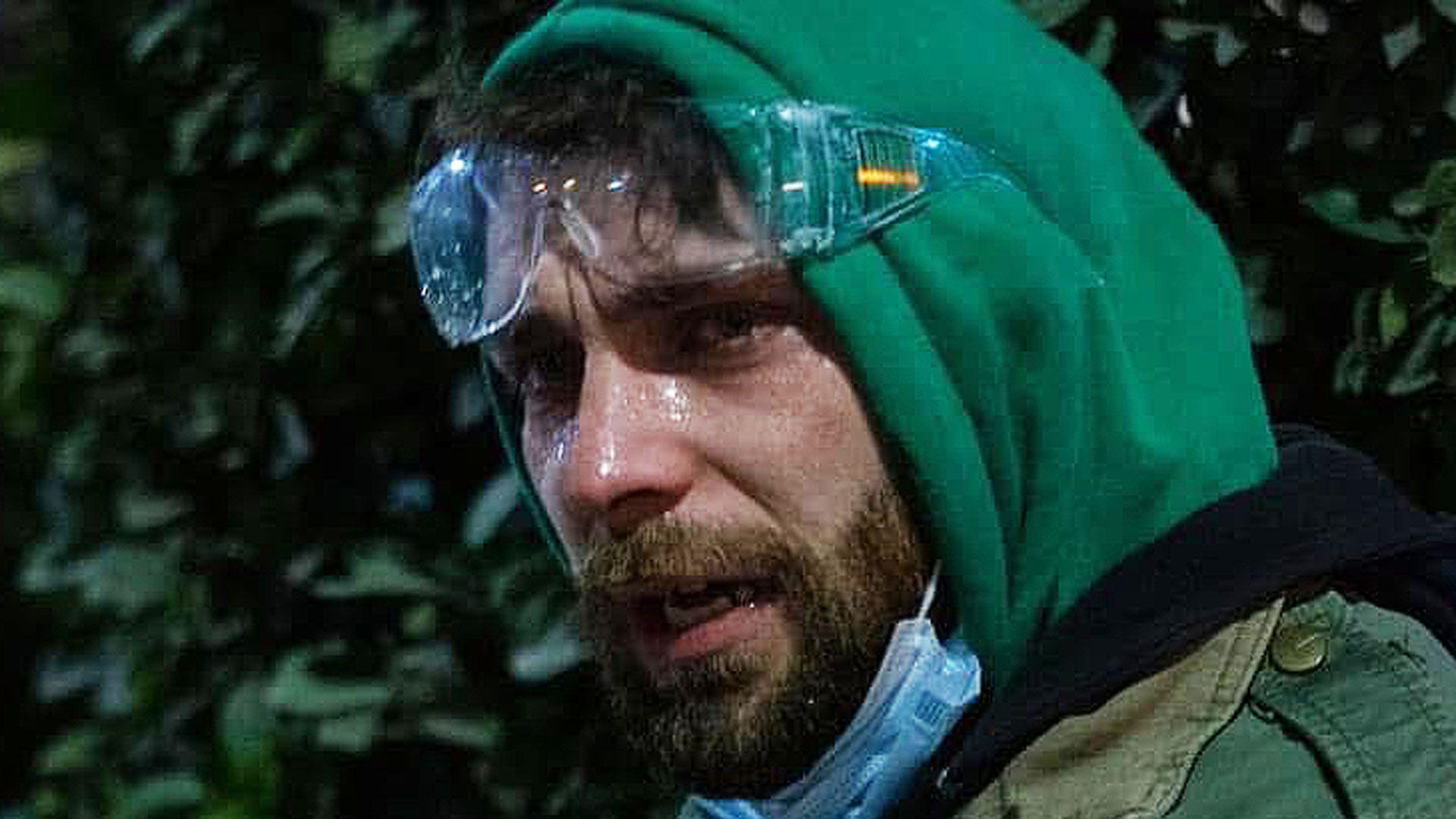 A young man in a green hoodie and goggles pulled up to his forehead is streaming from his eyes