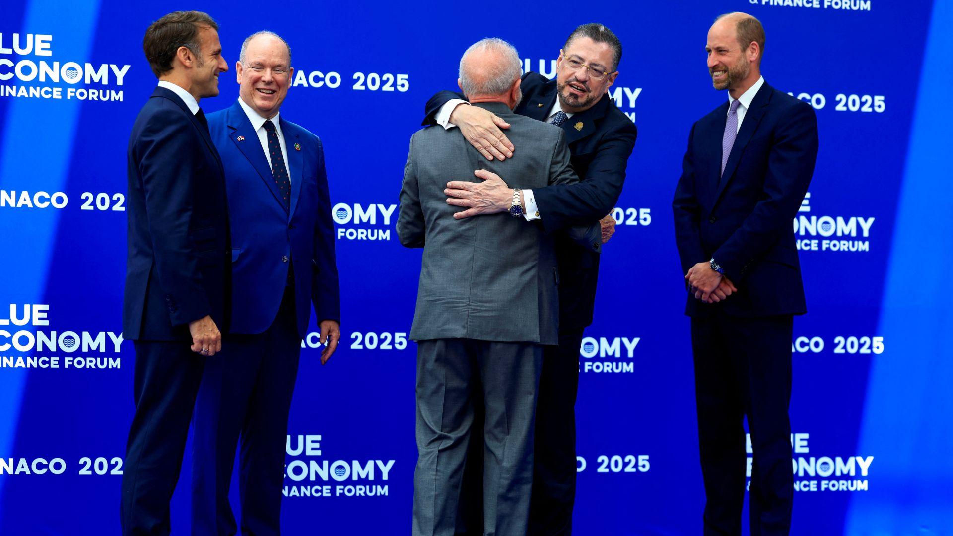 French President Emmanuel Macron, Prince Albert II of Monaco, Brazil's President Luiz Inacio Lula da Silva, Costa Rica's President Rodrigo Chaves Robles, and Prince William greet each other at the forum, standing in front of a blue wall with the Blue Economy logo written on it.