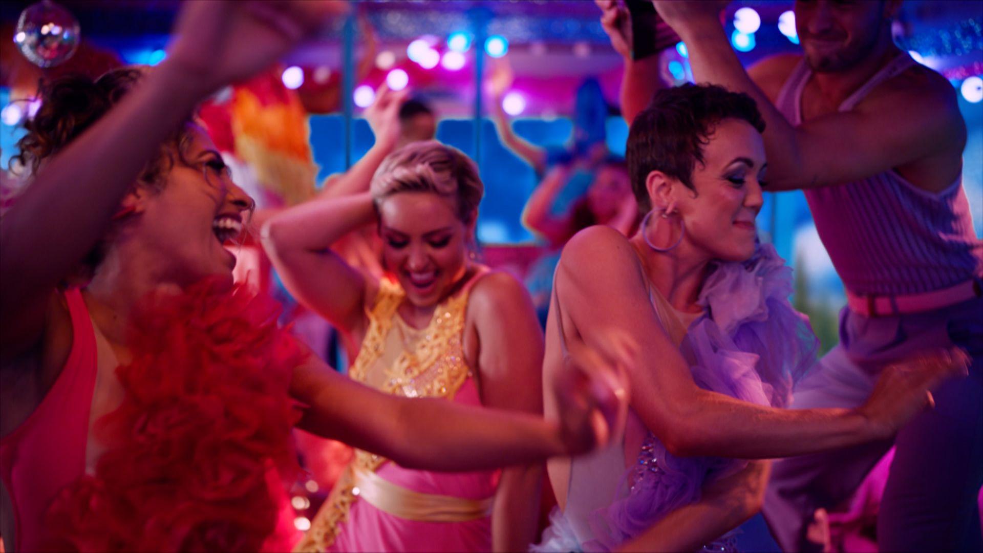 Strictly Come Dancing dancers in colourful outfits on a bright pink party bus