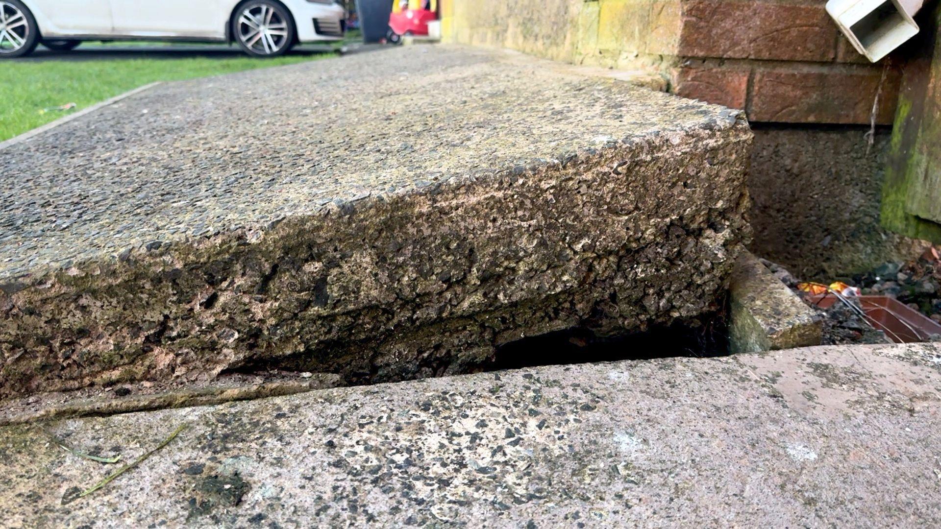 A large grey stone sits at an angle above the ground