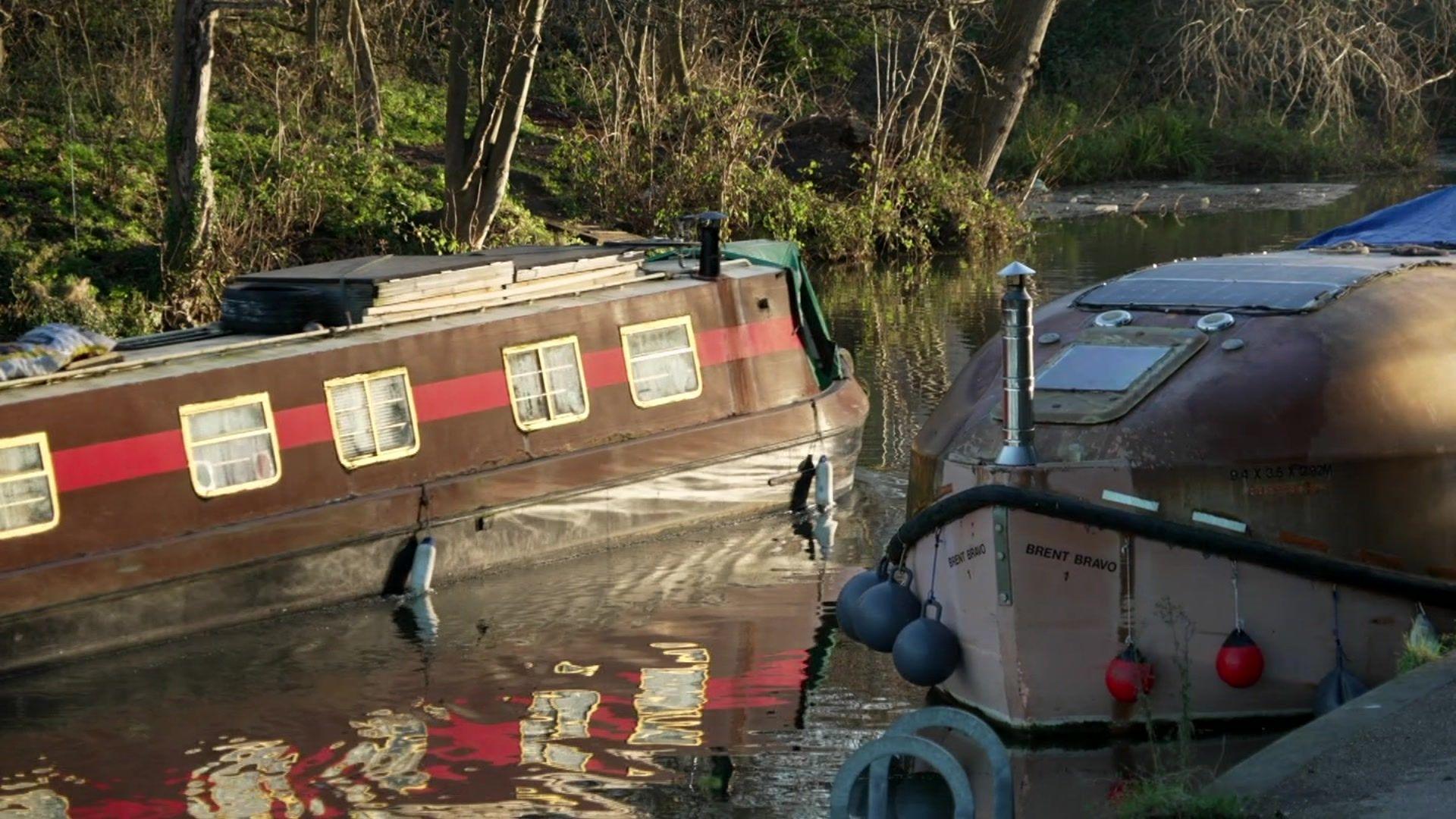 A houseboat travels along the river whilst passing a moored houseboat