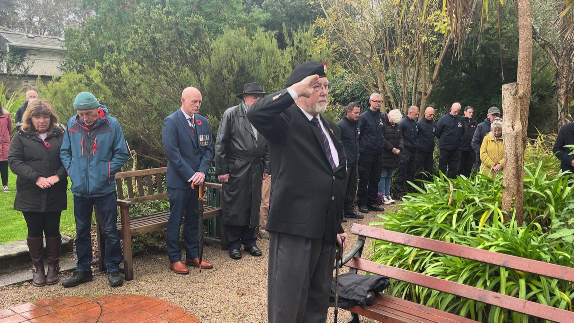 A veteran salutes while members of the public bow their heads during an Armistice Day service in Penzance's Penlee Park.
