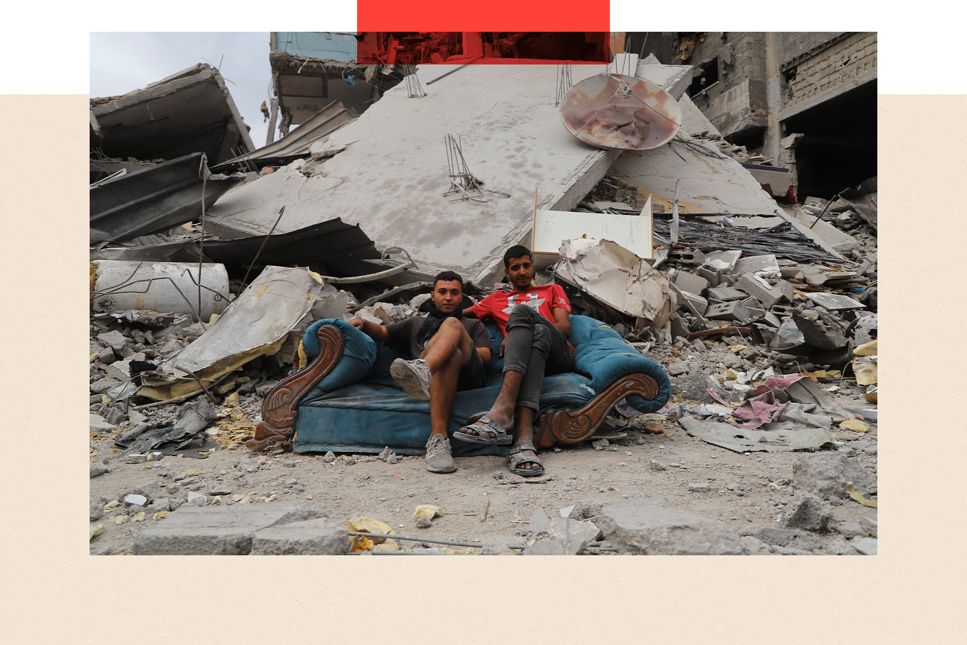 Two men sit on a coach amongst rubble