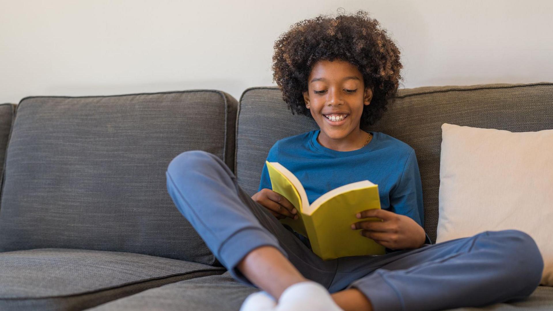 little boy on sofa enjoying reading a book