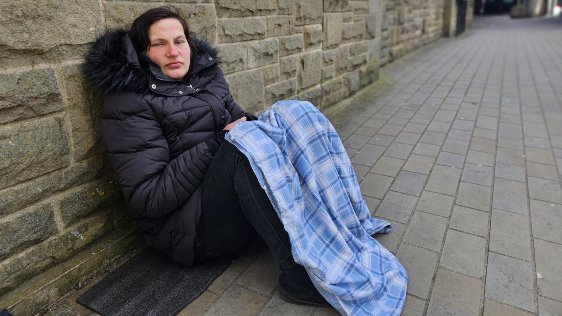 Leena resting against a wall with a blanket over her lap