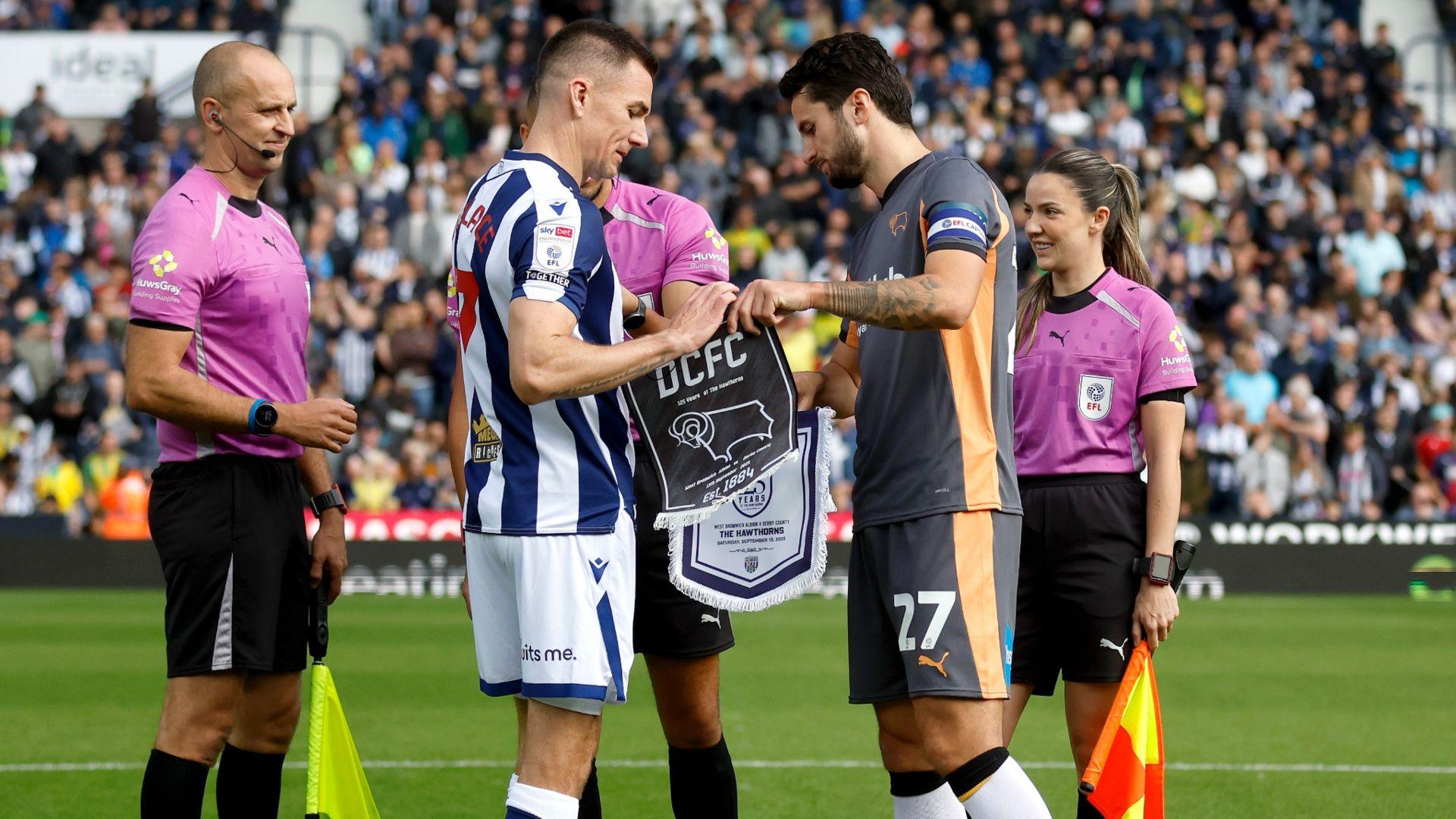 West Brom's Jed Wallace on the left and Derby County's Lewis Travis exchange club's pennants