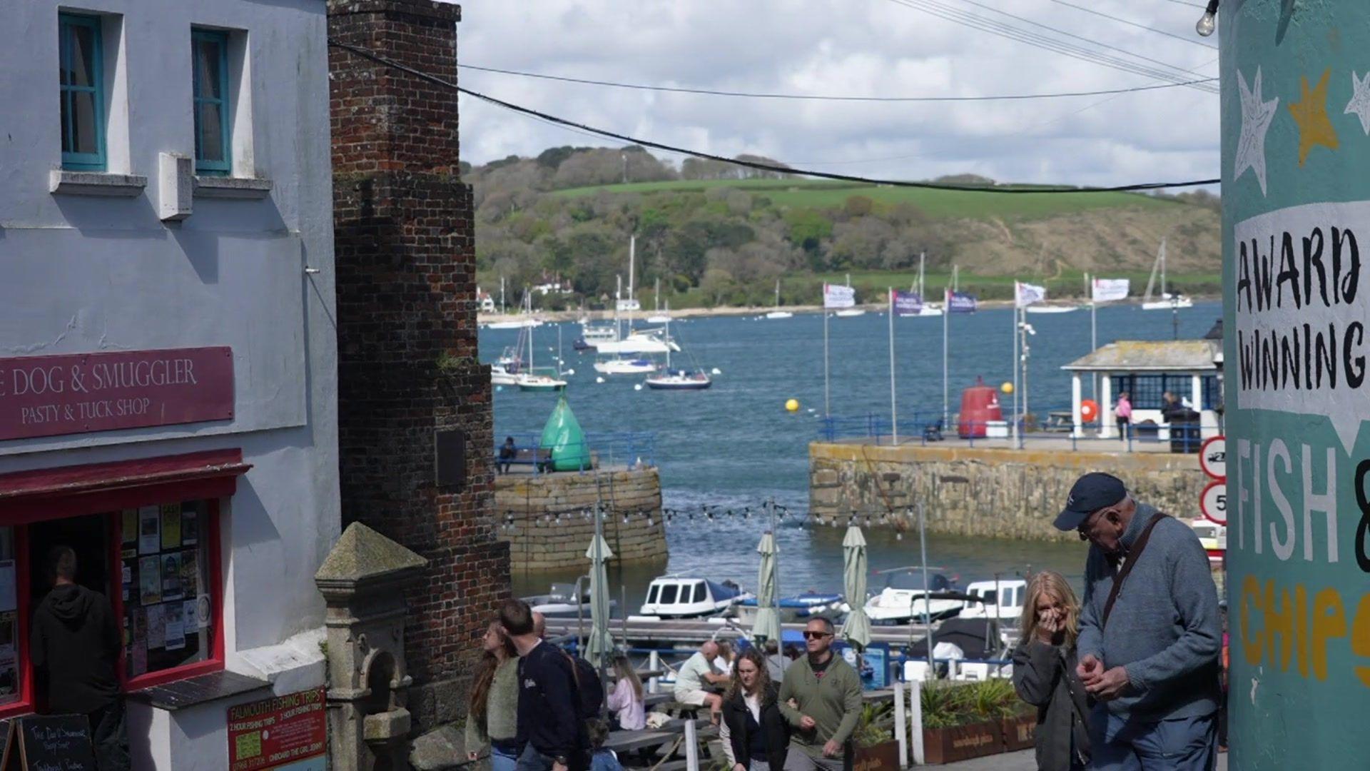 Seaside scene with people a harbour and boats.
