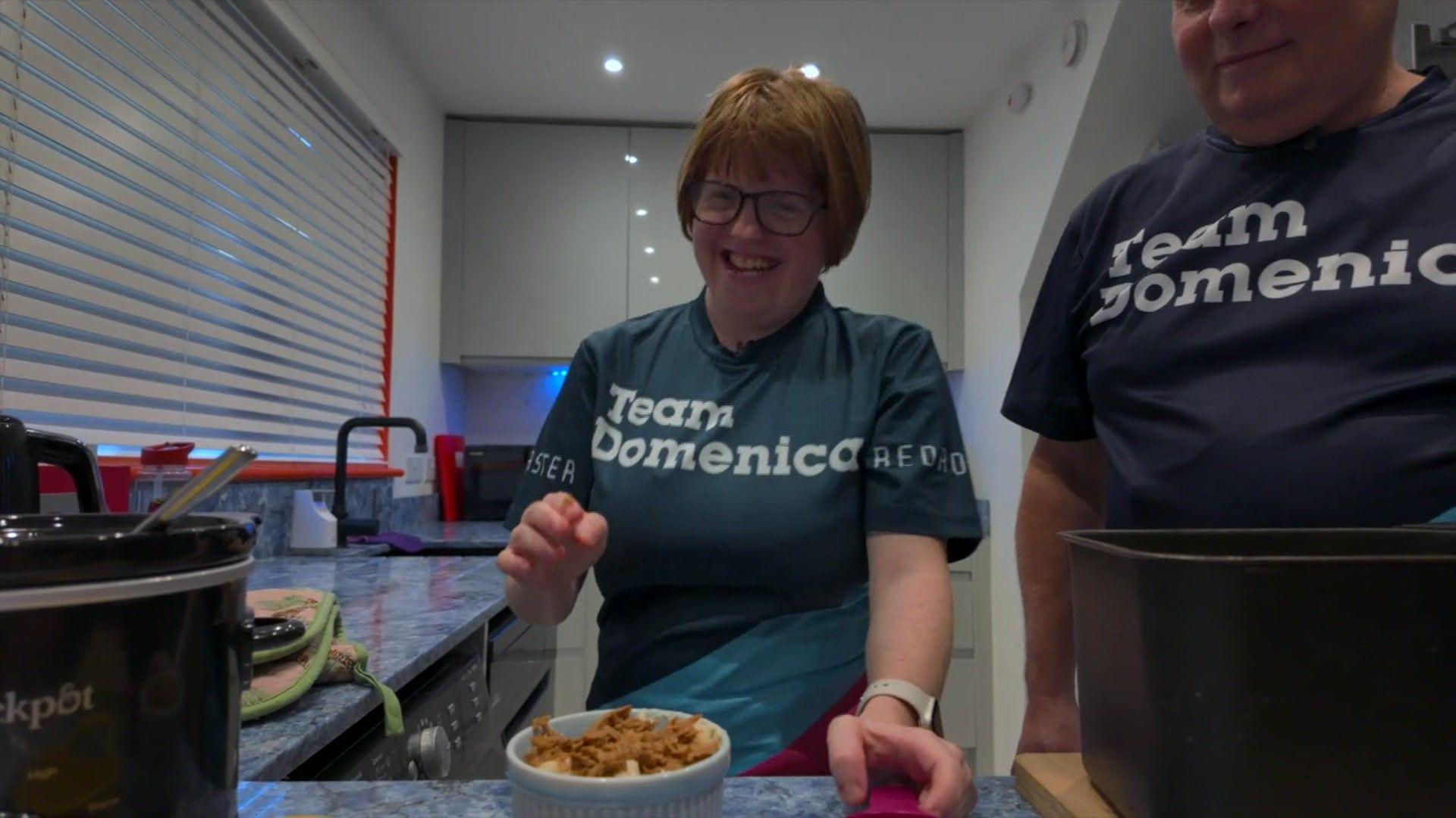 A woman smiles while preparing some food.