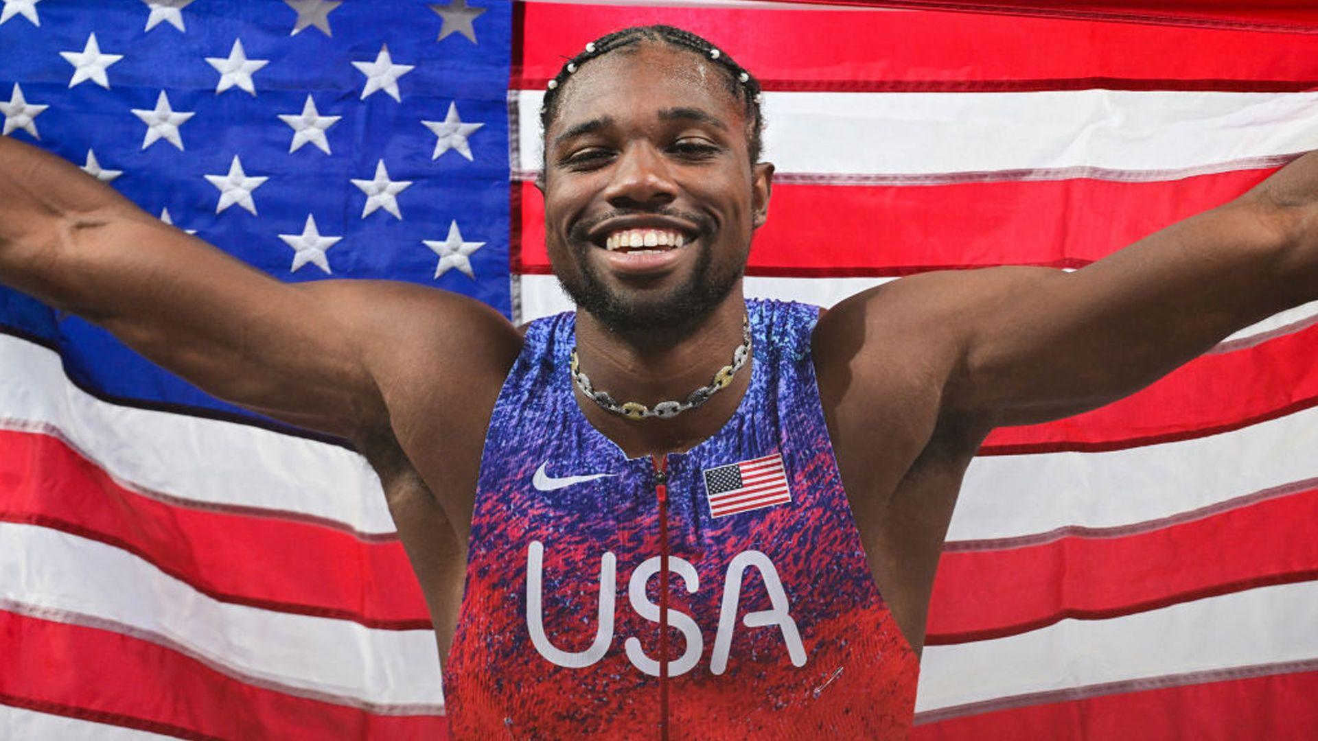 noah lyles poses with an american flag