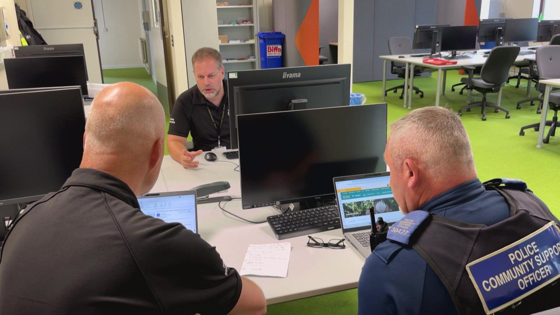 Two trading standards officers and a police community support officer sit at a desk planning the day's work.