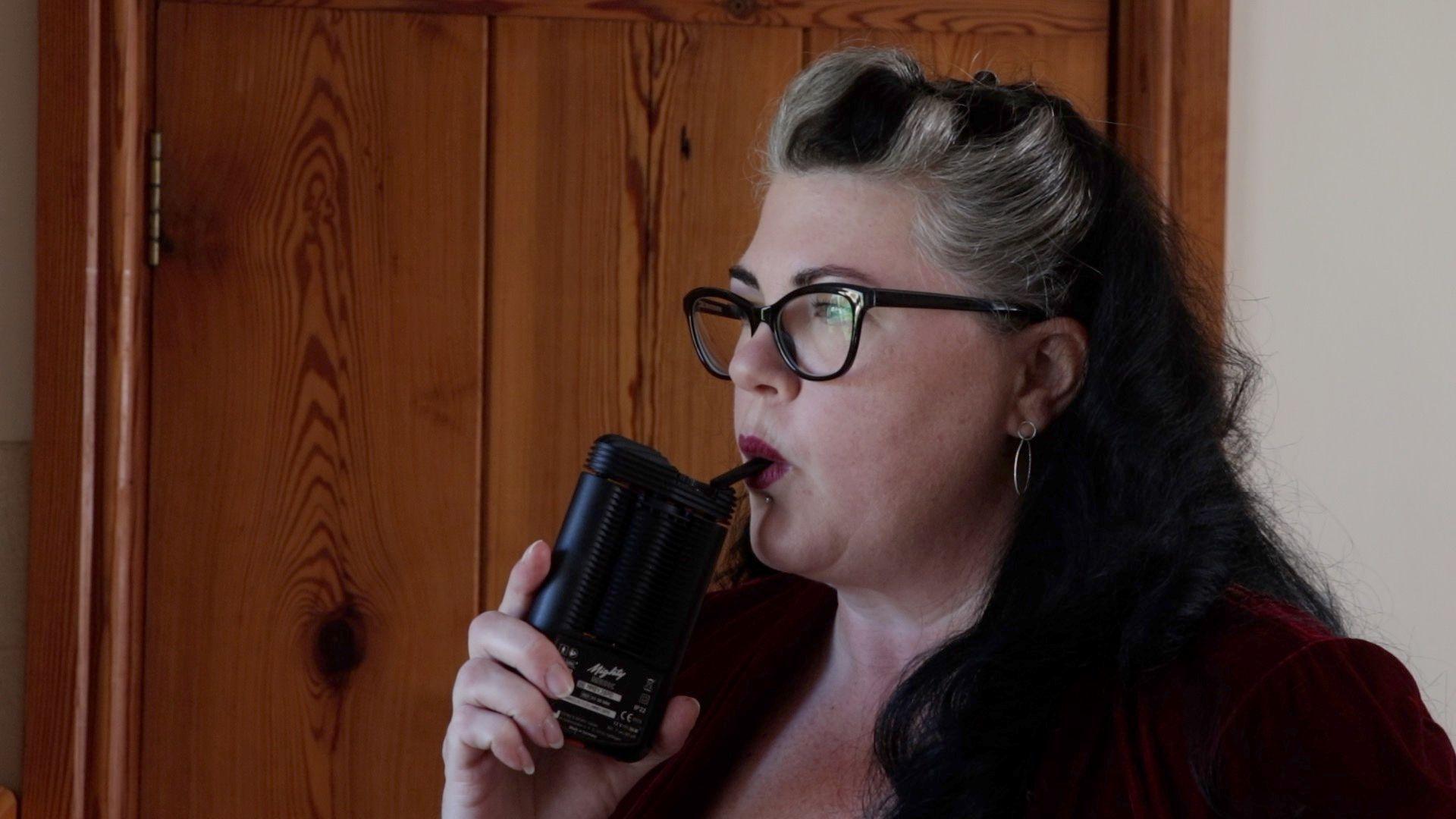 Denise Clark, who wears glasses and has black hair with blonde streaks, uses a black vape at home.