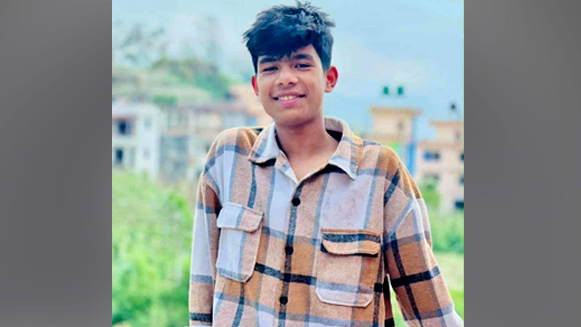 Abhishek Chaulagain, 22, is smiling and wearing a brown and white check shirt