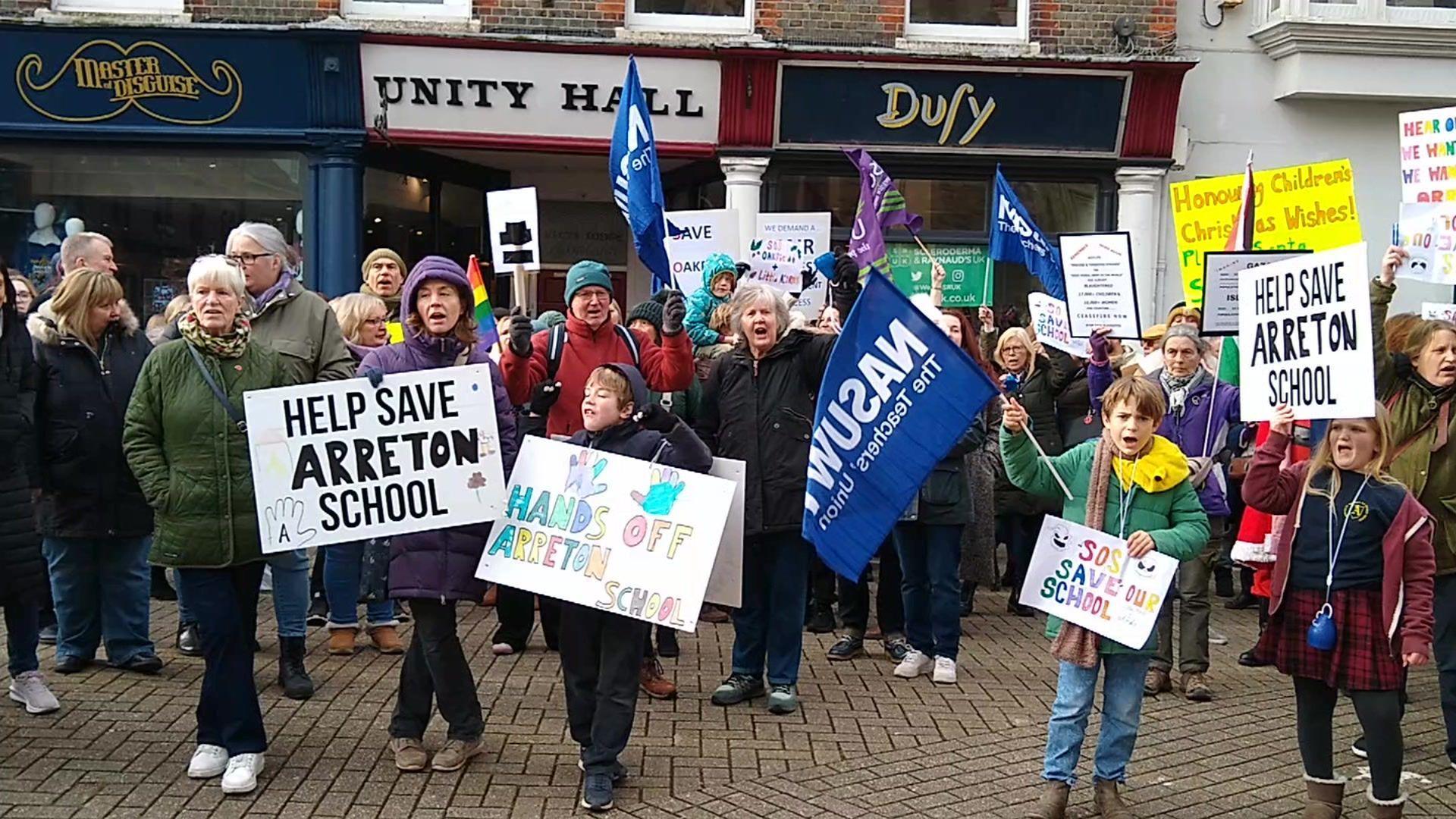 Crowds of people of all ages gathered on the street holding banners 