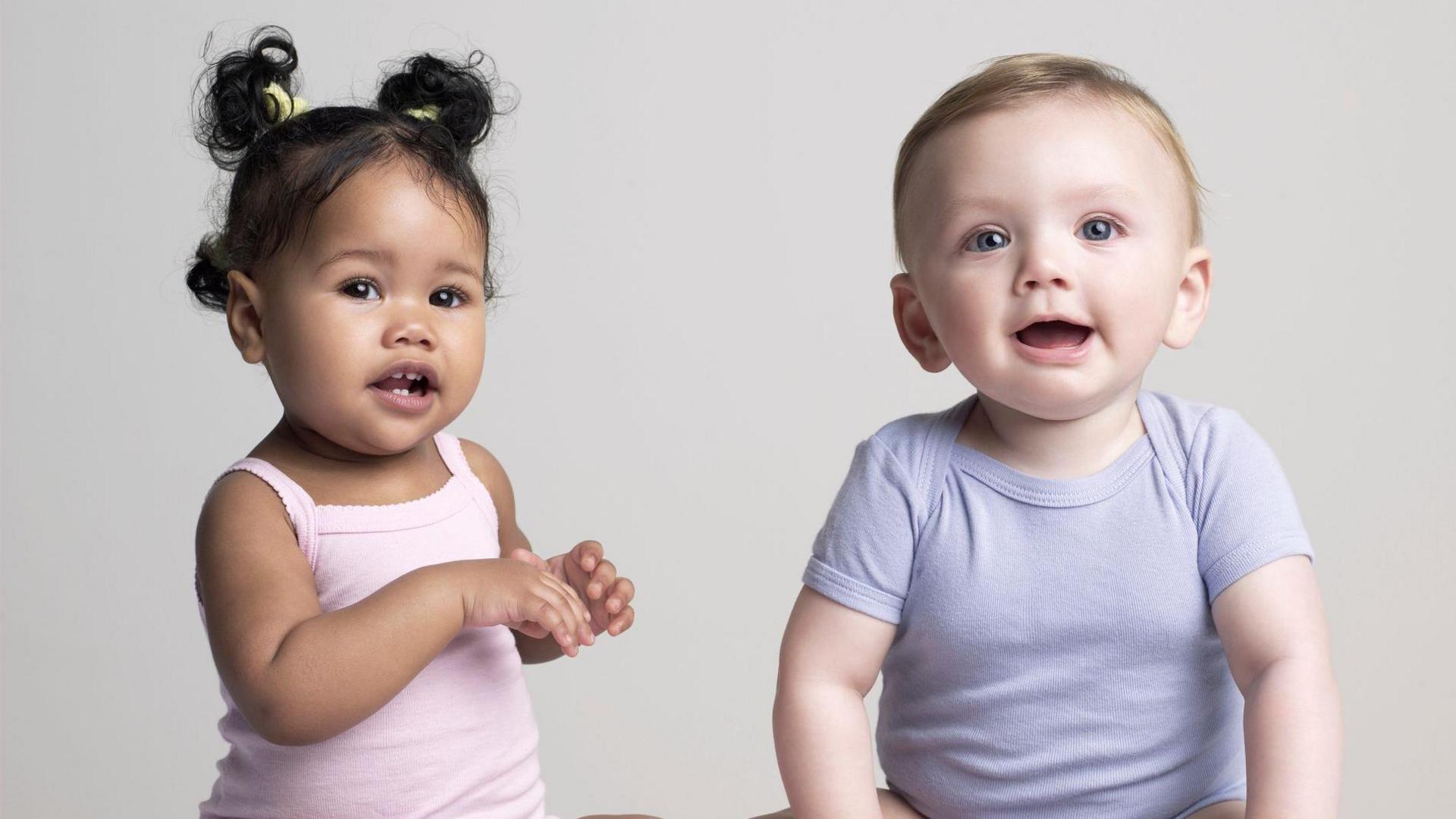 two babies in baby-grows sitting next to each other