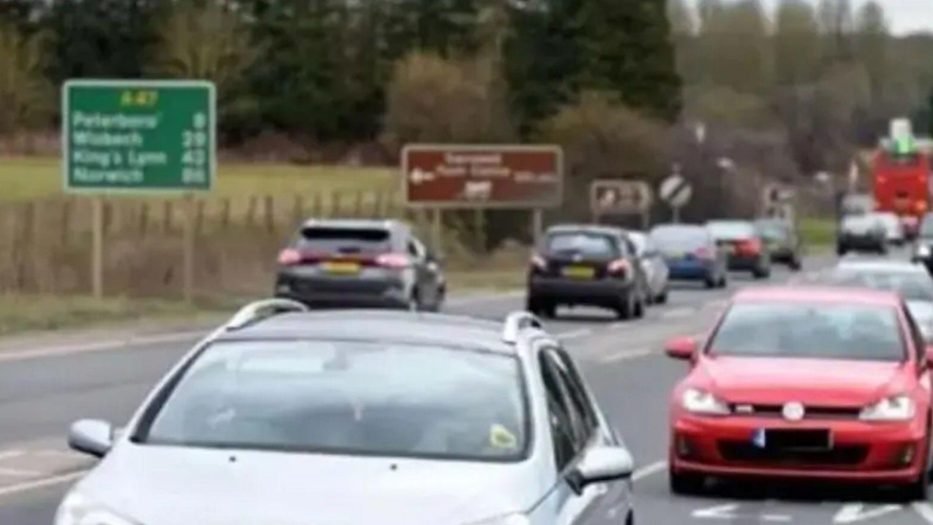 Cars on both sides of the road and a green A47 sign in the background