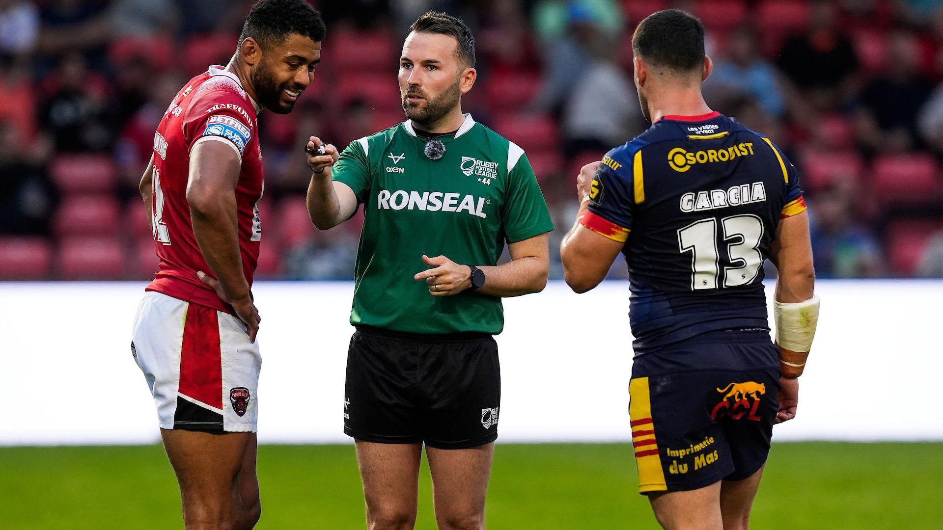 Super League referee Liam Moore discusses a decision with Salford's Kallum Watkins (left) and Catalans Dragons Ben Garcia (right)