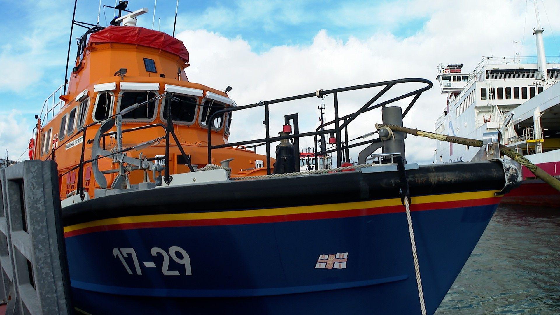 Close up of the lifeboat which is docked in the water. The vessel is blue and orange. It has 17-29 painted on the side. 