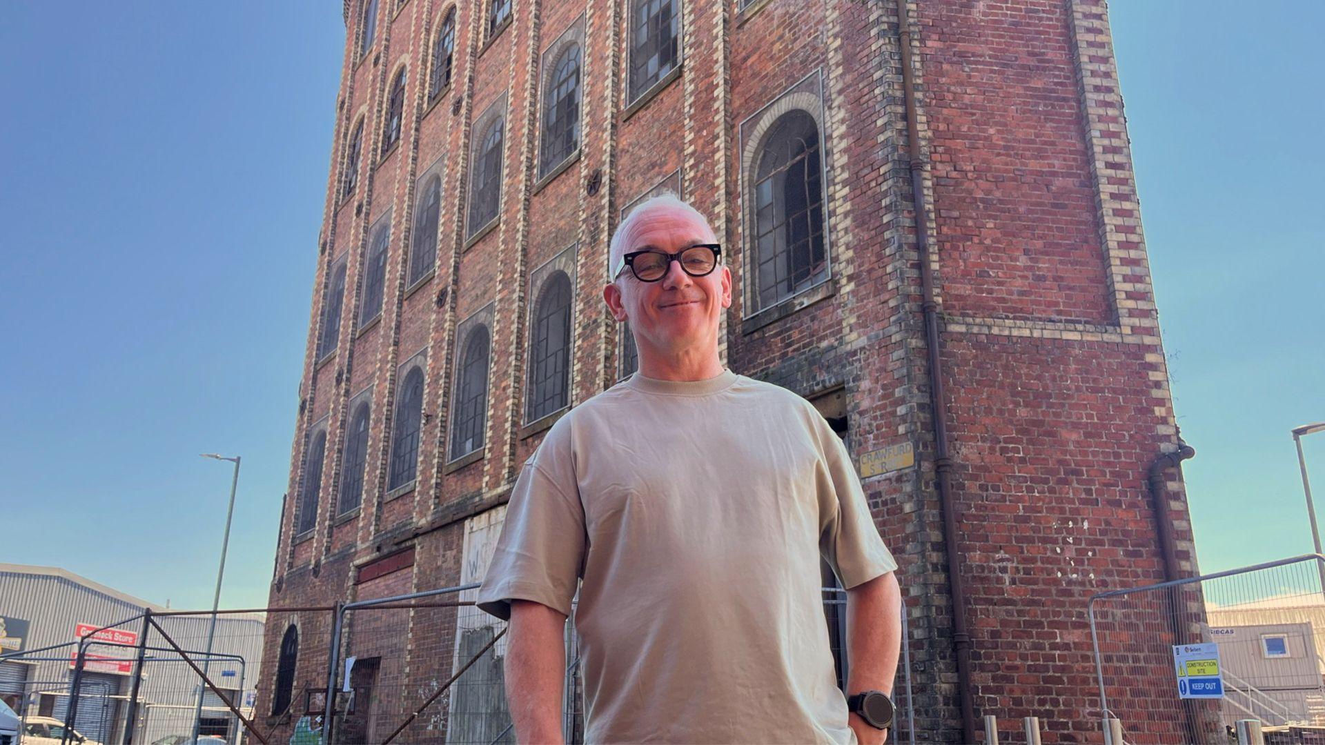 Derek Mitchell stands successful beforehand of an aged ceramic concern gathering with gangly arched windows and metallic fencing.