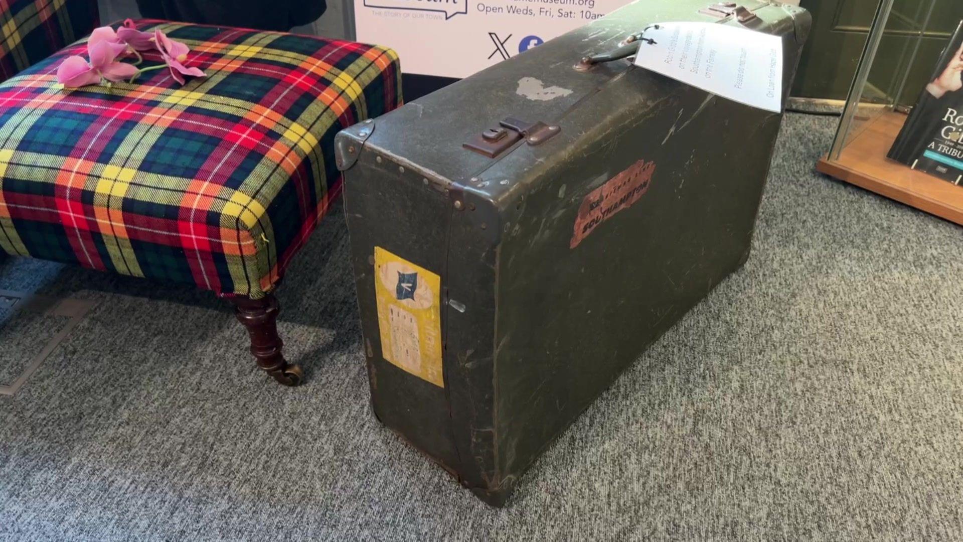 A slightly weathered old suitcase next to a tartan footstool.