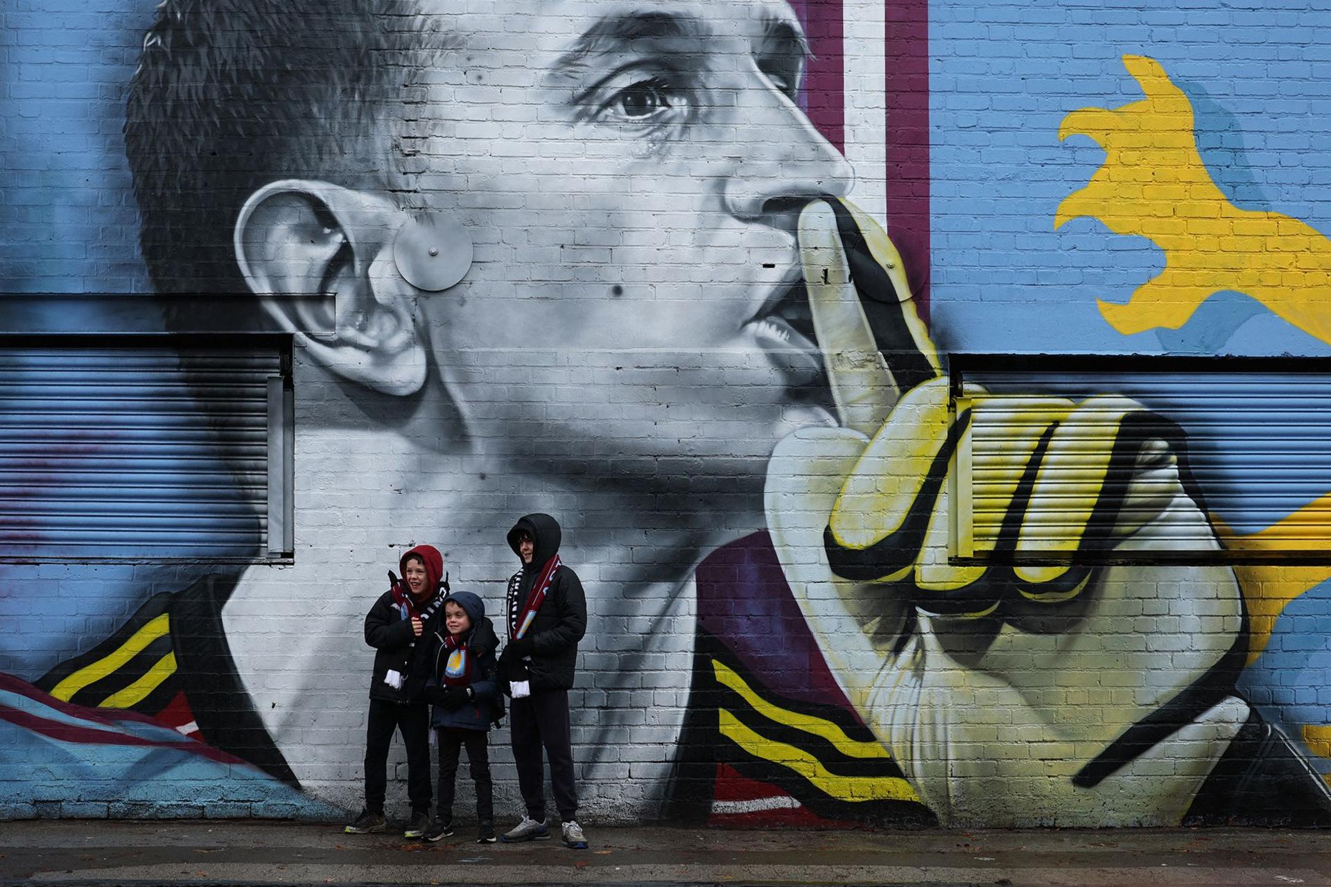 Aston Villa fans pose beside a mural of goalkeeper Emiliano Martinez before the Premier League match against Southampton