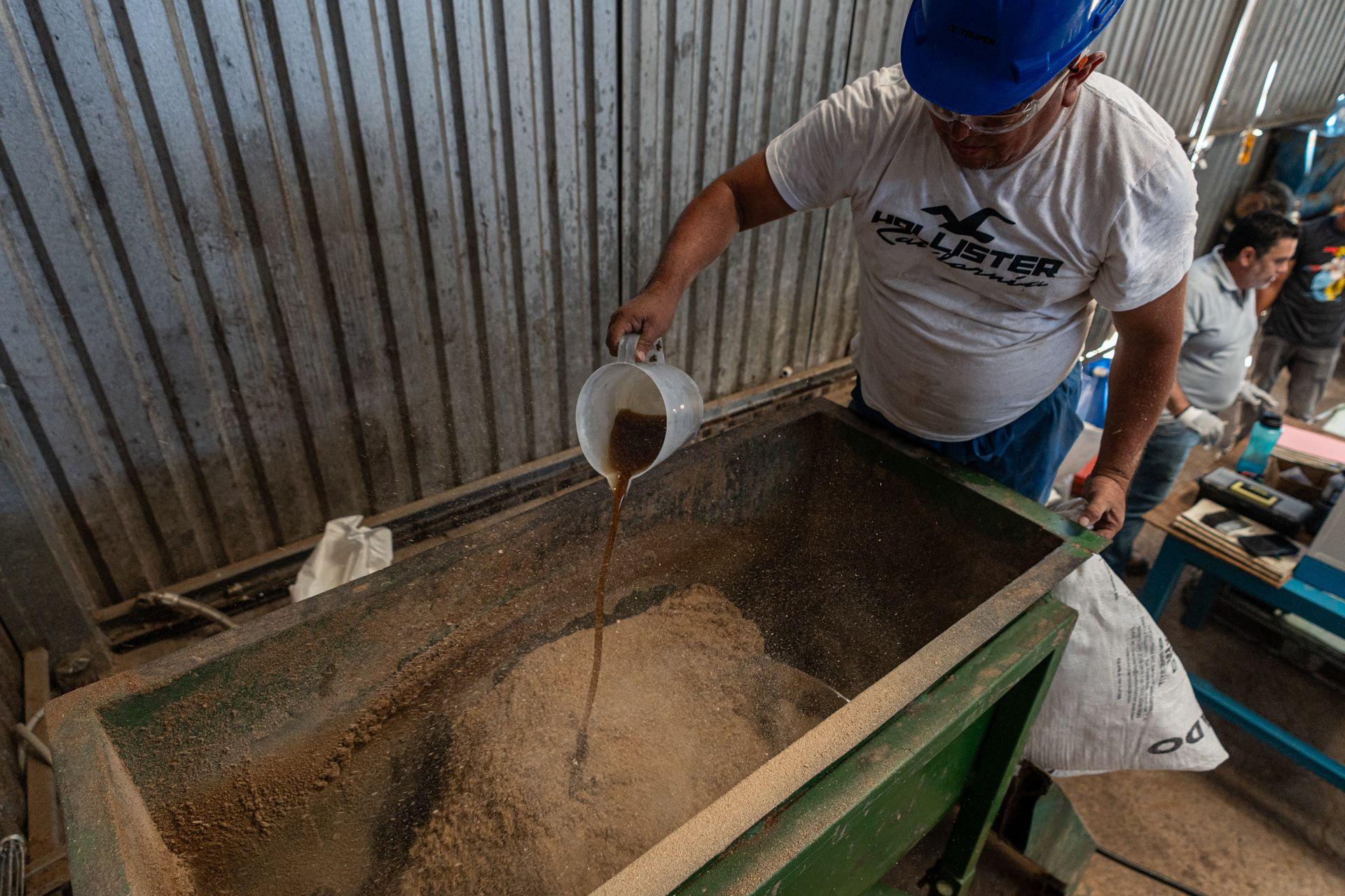 A worker pours beef grease into a mix which will be turned into dog food