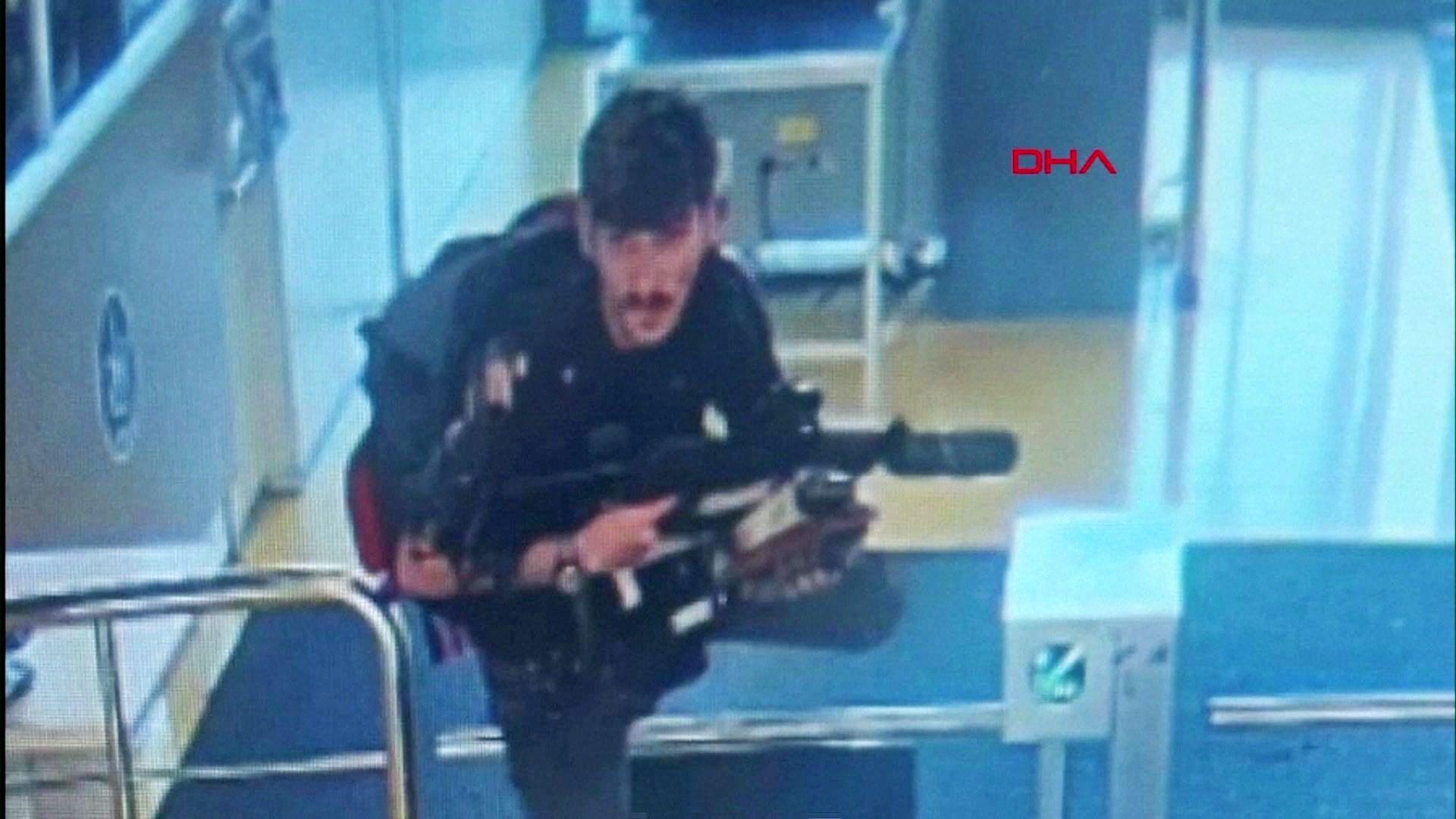 One of the suspects pictured on CCTV climbing over a turnstile holding a gun at the entrance of Turkish Aerospace Industries' headquarters