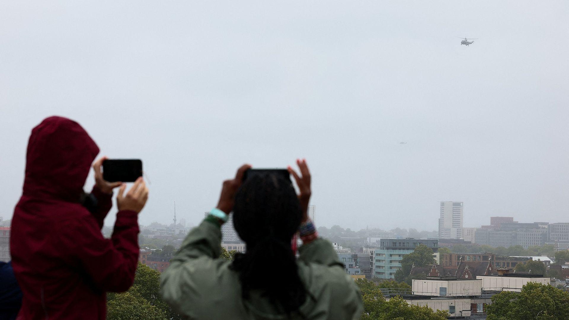 People watch as a helicopter believed to be carrying U.S. President Donald Trump flies after leaving the U.S. ambassador's residence Winfield House, on the way to Windsor, in London, Britain, September 17, 20