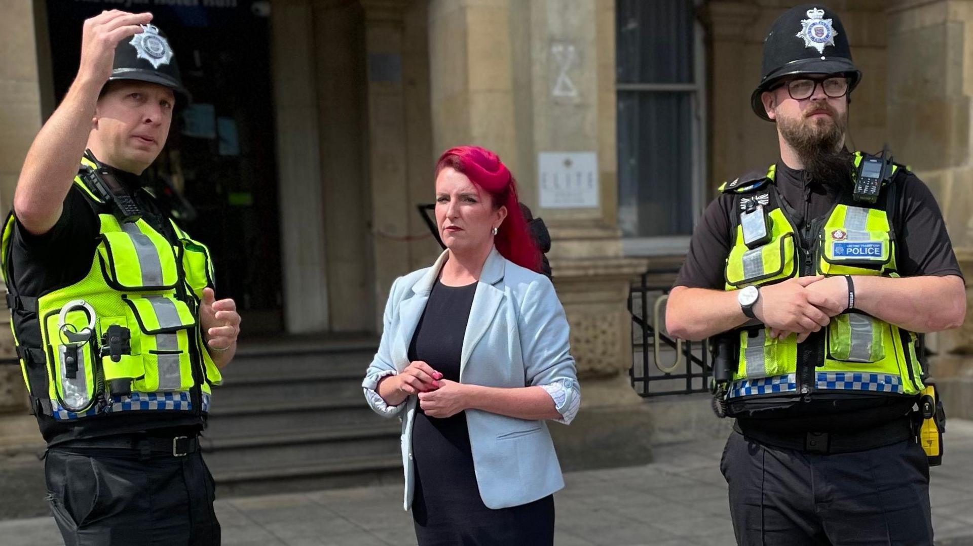 Transport Secretary Louise Haigh standing in the middle of two police officers with the one on the left raising his arm in the air