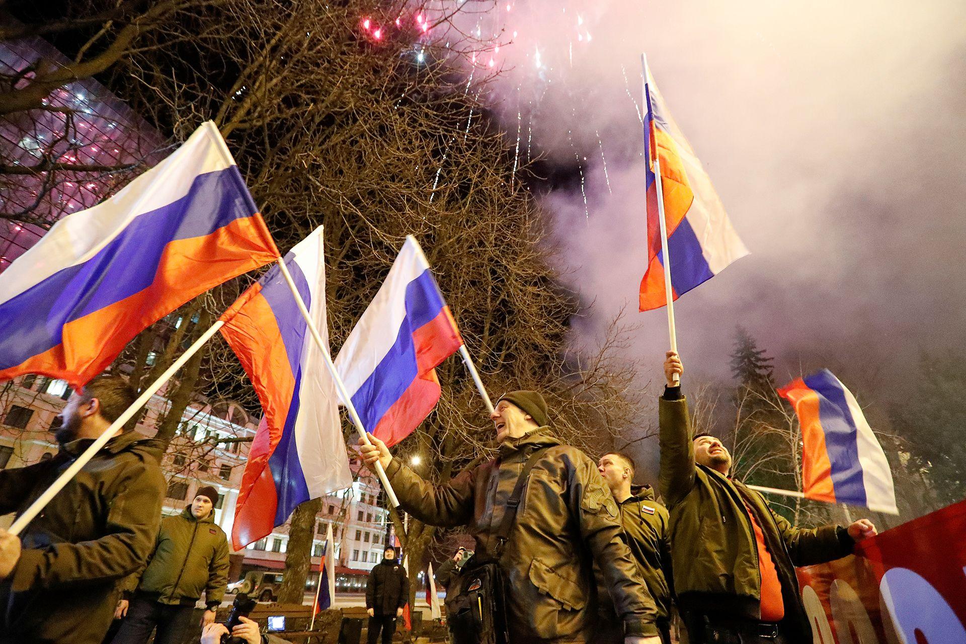 Pro-Russian activists wave Russian flags while celebrating in a street as fireworks explode in the sky, in a square in Donetsk, Ukraine on 21 February 2022.