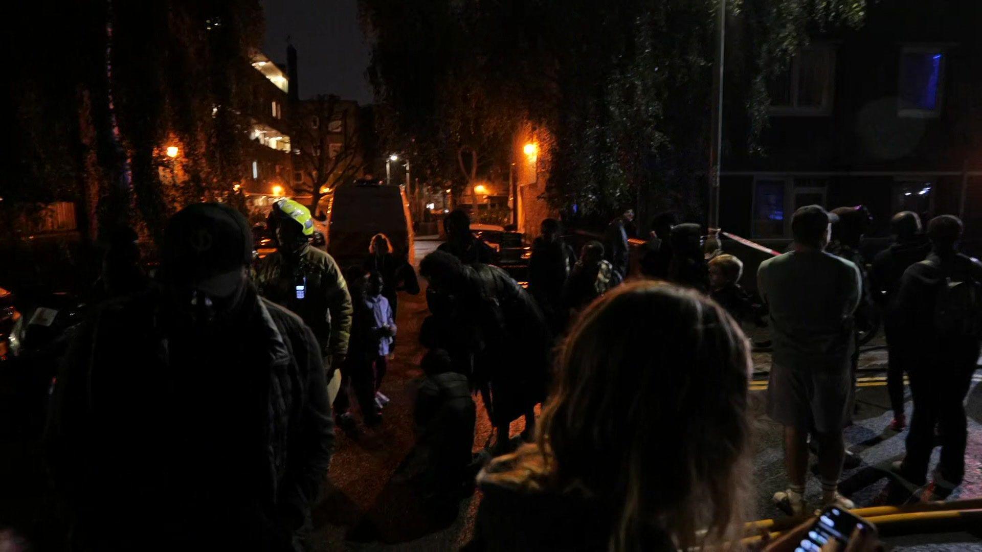 Several people standing around in the dark, with fire officers among them