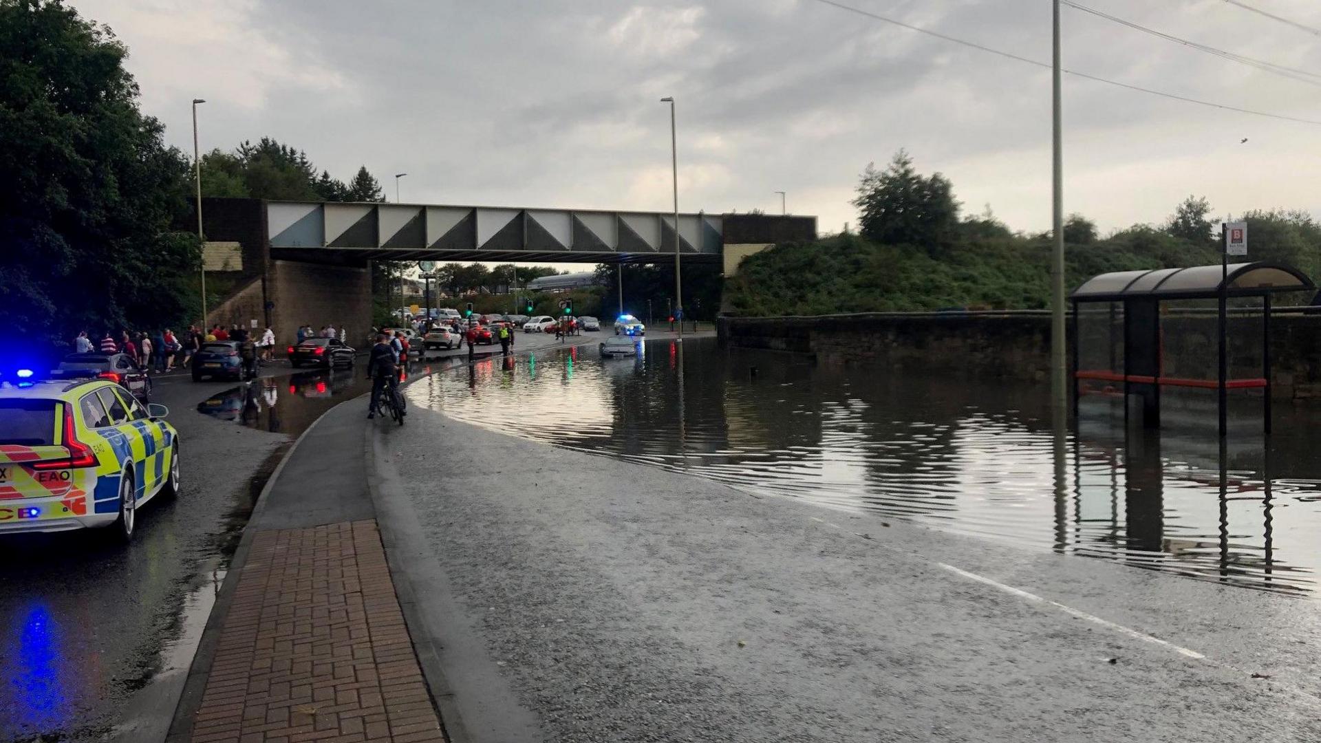 Police car and a flooded road with a car trapped