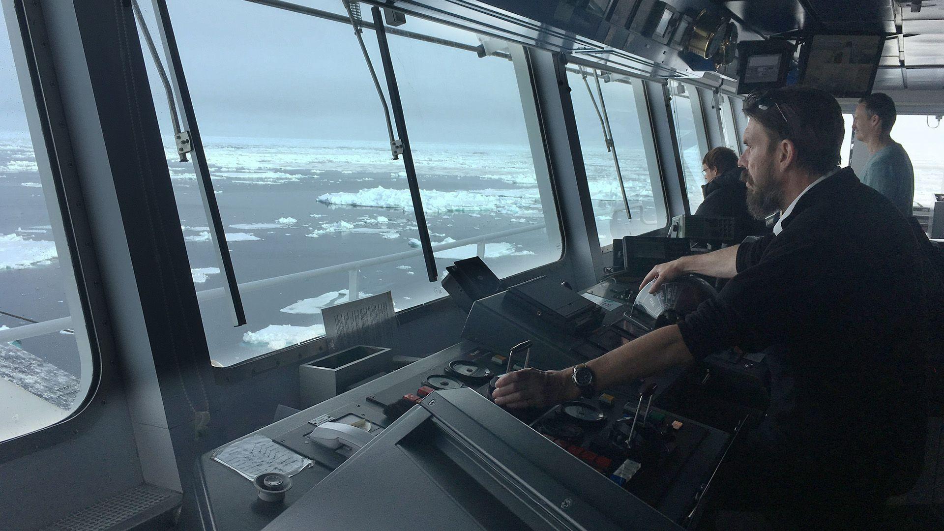 Pharos captain Simon Wallace on the bridge of the vessel Pharos looking out of the window while navigating through floating ice near South Georgia