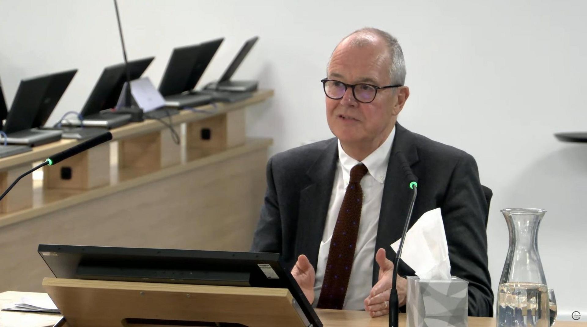 Lord Patrick Vallance, former government chief scientific adviser, giving evidence at the Covid-19 Inquiry, standing at lectern, wearing a dark suit