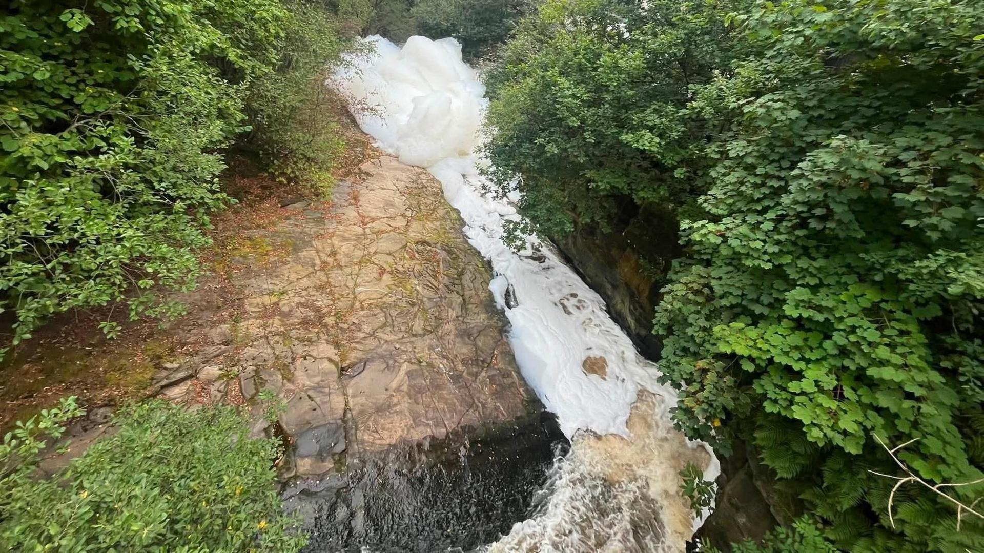 Large white clumps of foam in a river.