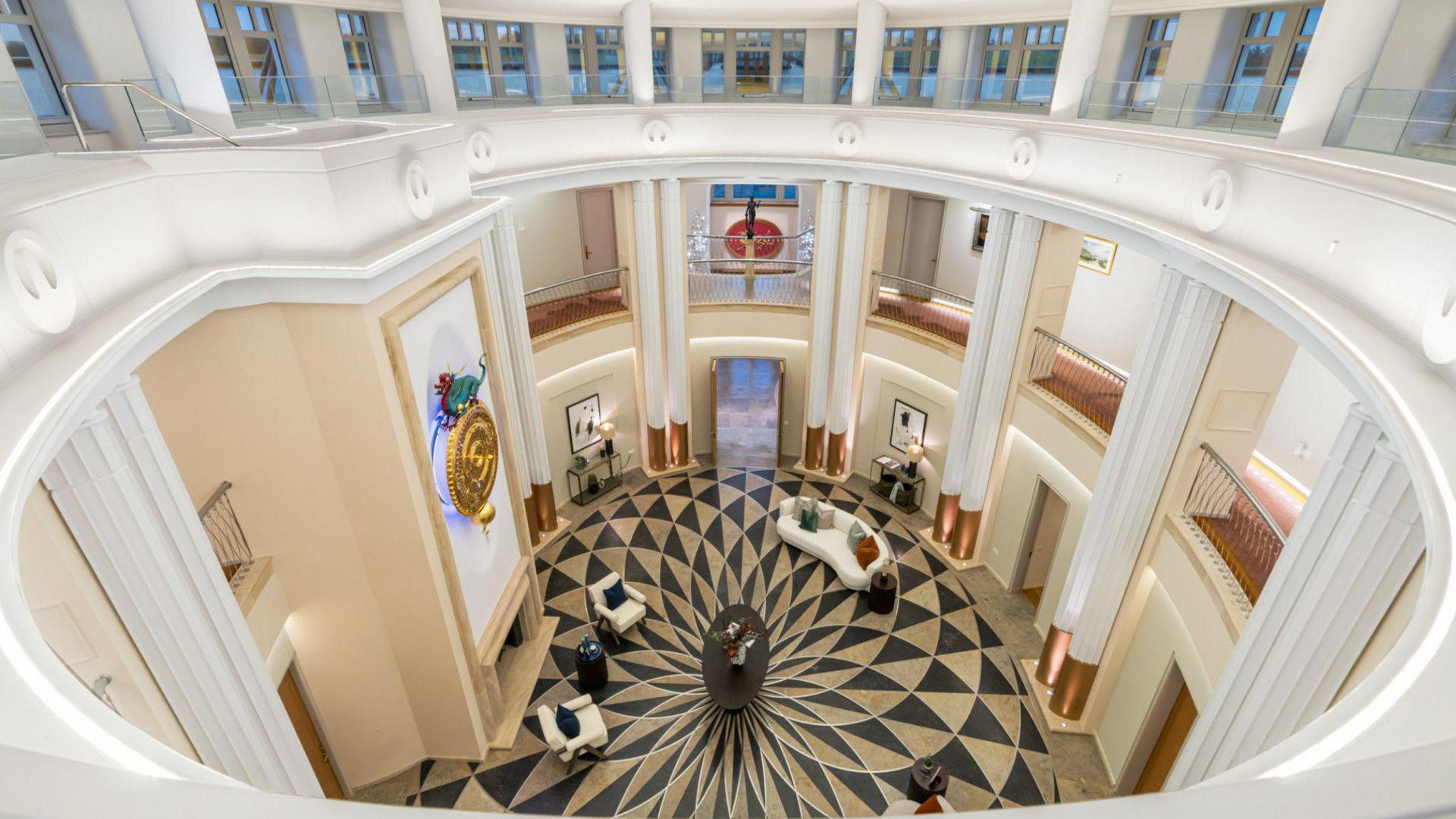The elliptical central atrium, which shows white balconies framing a black and white patterned floor below.