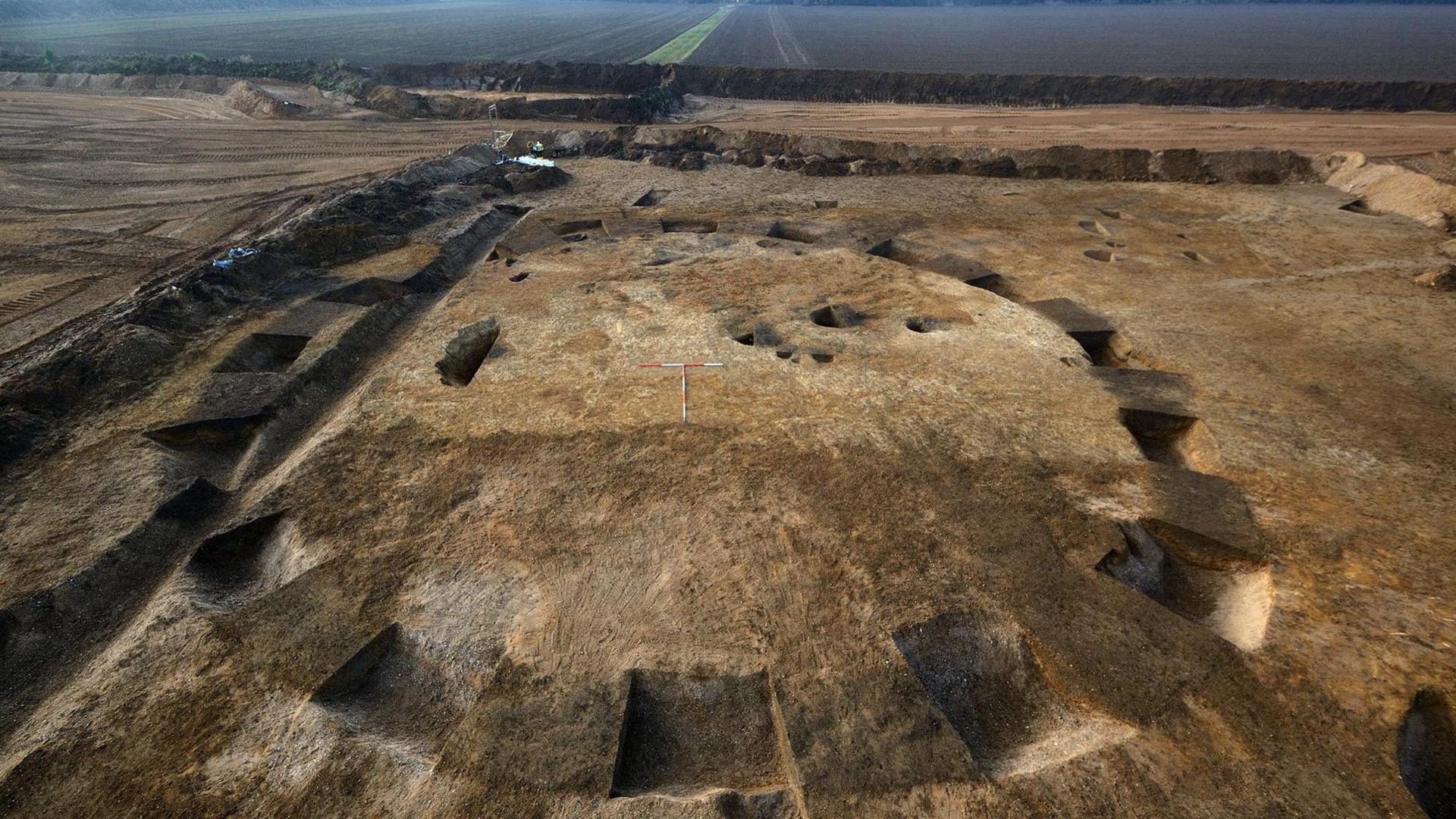 Aerial view of an early Bronze Age burial mound with a hedgerow and fields in the distance