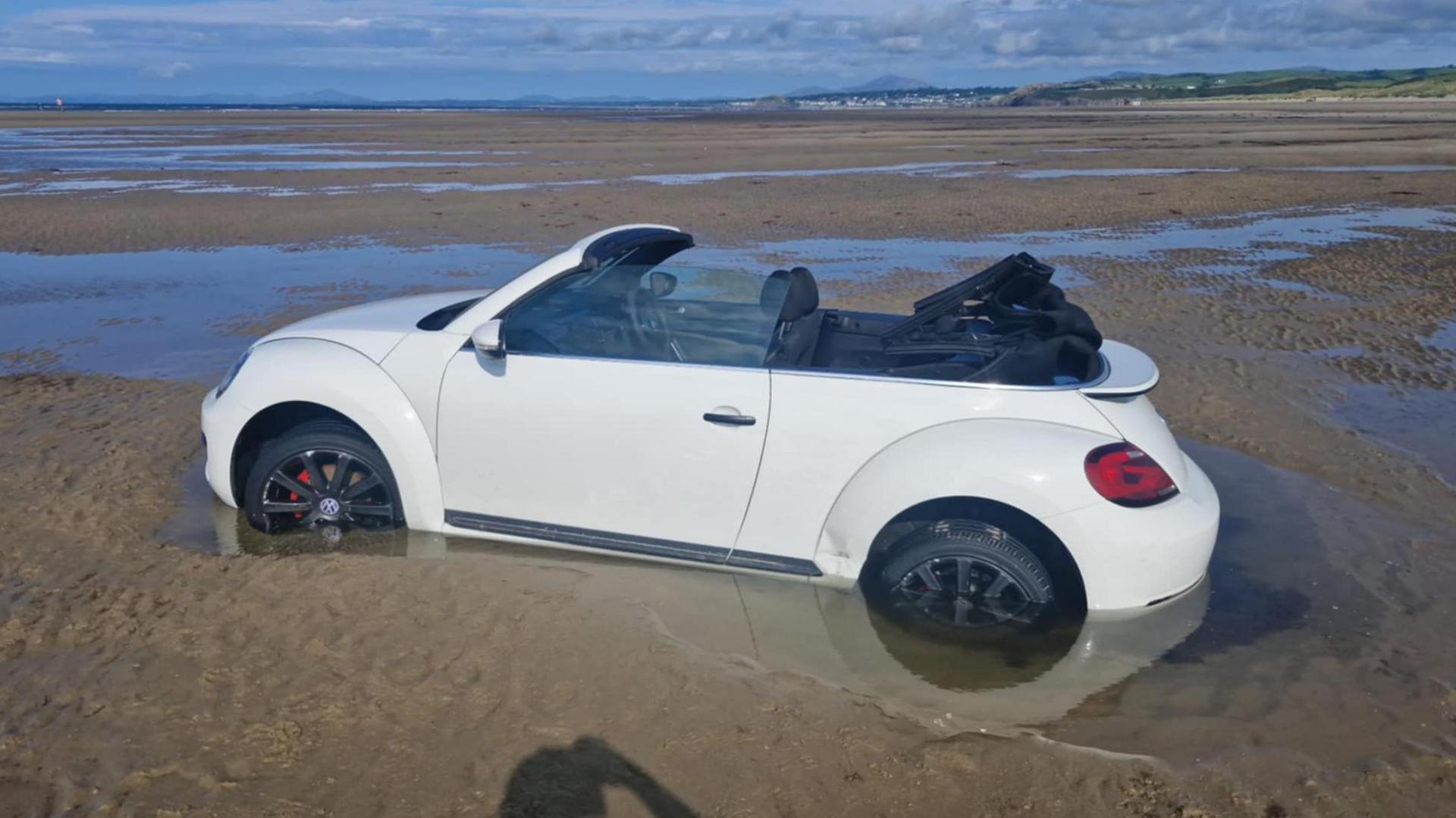 Llun o VW Beetle yn sownd ar y traeth