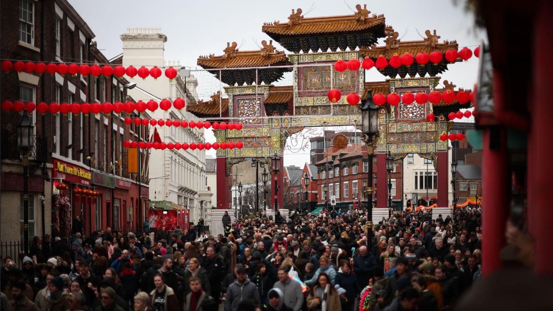 Liverpool's Chinese Arch with crowds of people and red lanterns hung across the street during Chinese New Year celebrations in 2024. 